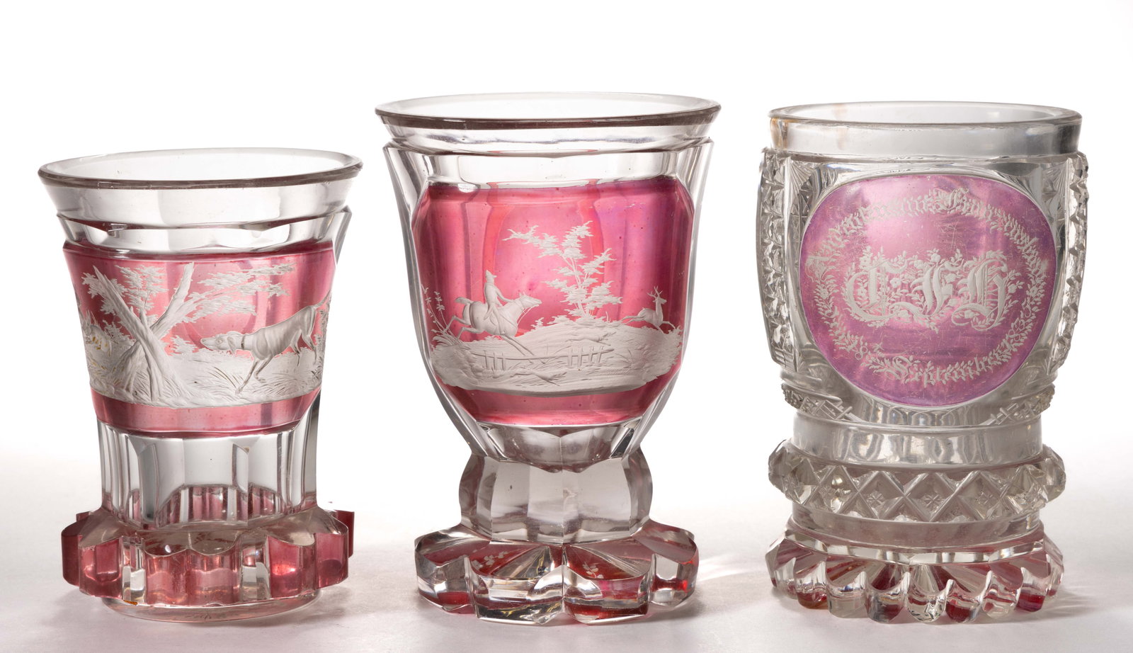 BOHEMIAN CUT, ENGRAVED, AND STAINED / DECORATED GLASS BEAKERS / DRINKING GLASSES, LOT OF THREE: BOHEMIAN CUT, ENGRAVED, AND STAINED / DECORATED GLASS BEAKERS / DRINKING GLASSES, LOT OF THREE, the smallest example featuring cut paneling on the thistle-form body and having a single rectangular cra