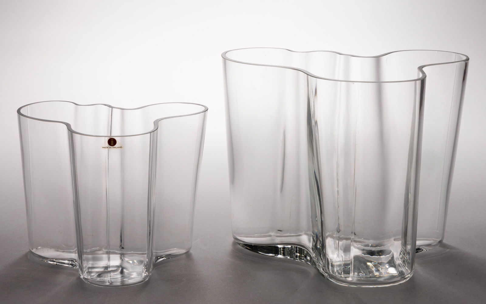 ALVAR AALTO (FINNISH, 1898-1976) FOR IITTALA SAVOY VASES, LOT OF TWO: ALVAR AALTO (FINNISH, 1898-1976) FOR IITTALA SAVOY VASES, LOT OF TWO, colorless, free-form with polished rim, each with acid signature under base, small example also marked for Iittala and dated 1881-