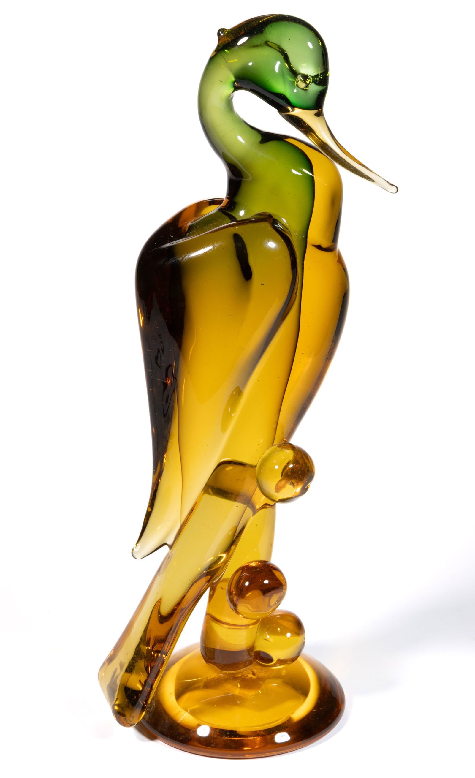 MURANO HERON ART GLASS SCULPTURE: MURANO HERON ART GLASS SCULPTURE, shaded green to amber, depicting a heron/stork perched on a vertical pole with five applied orbs to the side, domed foot, polished pontil mark. 20th century. 15"