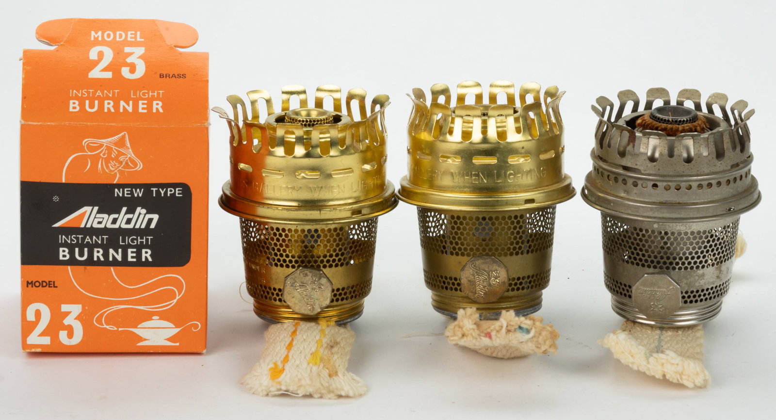 ALADDIN MODEL NO. 23 HEELLESS KEROSENE LAMP BURNERS, LOT OF THREE: ALADDIN MODEL NO. 23 HEELLESS KEROSENE LAMP BURNERS, LOT OF THREE, comprising two examples with a brass finish and one example with a nickel-plated finish, each with original flame spreader, one 