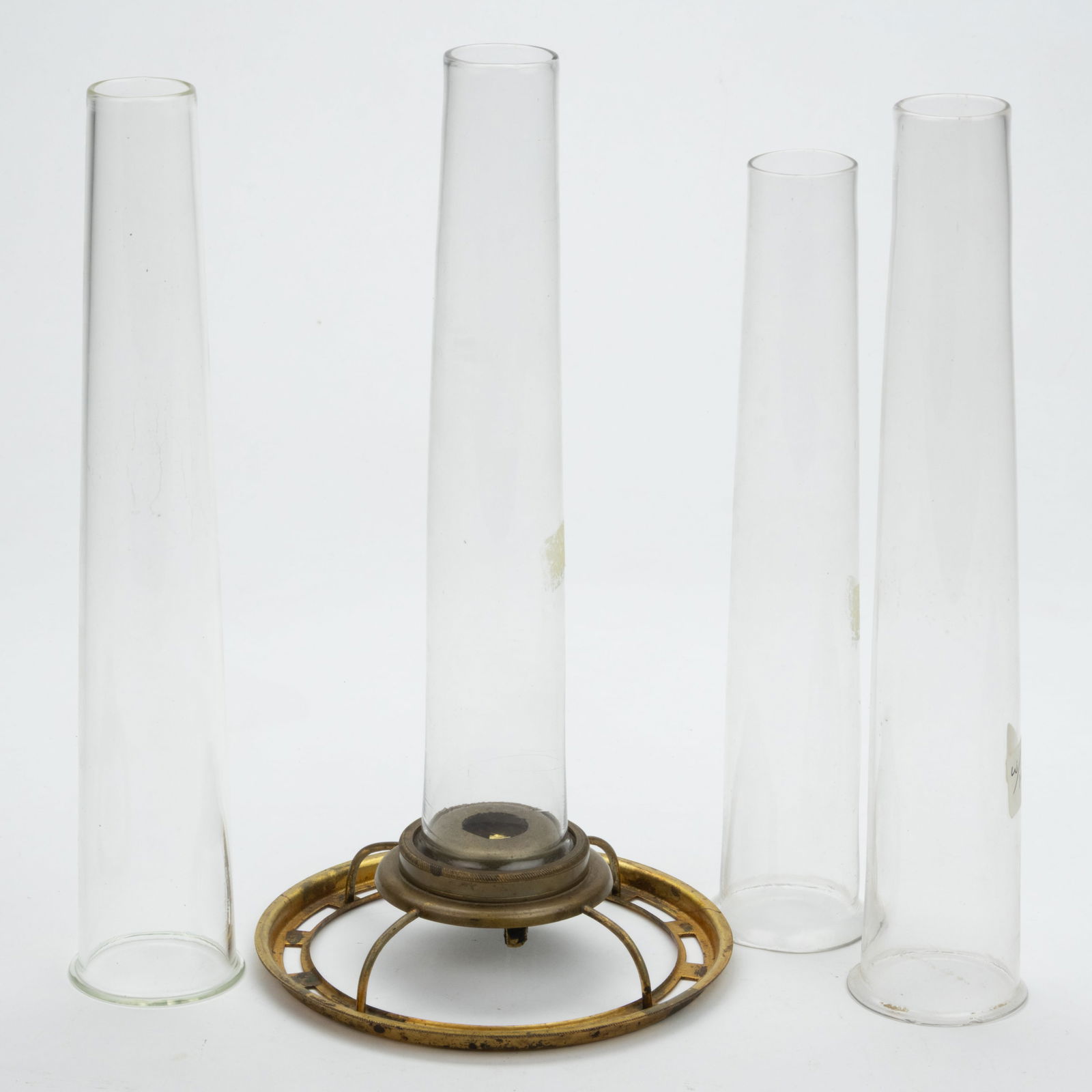 AMERICAN BRASS SOLAR BURNER COMPONENTS AND CHIMNEYS, LOT OF FOUR: AMERICAN BRASS SOLAR BURNER COMPONENTS AND CHIMNEYS, LOT OF FOUR, comprising of a burner with brass construction and including a shade ring with four connecting arms to the deflector, underside of the