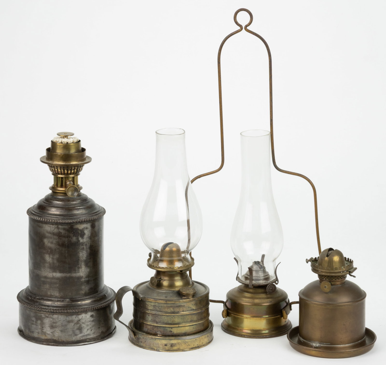 ASSORTED BRASS AND METAL LIGHTING ARTICLES, LOT OF FOUR: ASSORTED BRASS AND METAL LIGHTING ARTICLES, LOT OF FOUR, comprising two examples with E. Miller lip burners, one example with gimbal mounts and a saucer base, remaining with a strap handle and side-re