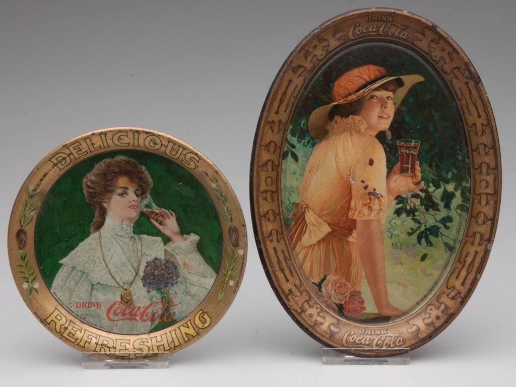 COCA-COLA CHANGE TRAYS, LOT OF TWO: COCA-COLA CHANGE TRAYS, LOT OF TWO, lithographed tin, 1906 circular and 1916 oval. First quarter 20th century. 4 1/8" D and 6" x 4 3/8". Provenance: From the collection of the late Betty Jane Renn, Su