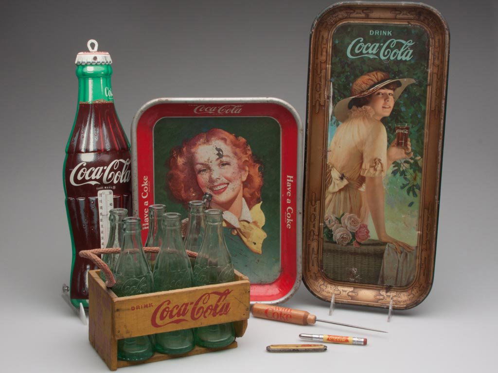 COCA-COLA VINTAGE ADVERTISING ARTICLES, LOT OF SEVEN: COCA-COLA VINTAGE ADVERTISING ARTICLES, LOT OF SEVEN, including a wooden carrier with bottles, two serving trays and a thermometer. 20th century. Thermometer 17" H. Provenance: From a Connecticut priv