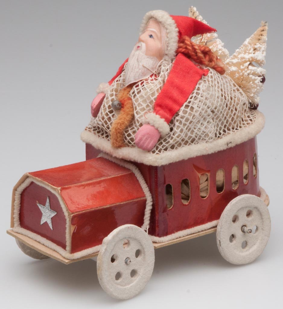 SANTA CLAUS IN AUTOMOBILE CANDY CONTAINER: SANTA CLAUS IN AUTOMOBILE CANDY CONTAINER, cardboard, celluloid and fabric, with two Christmas trees in back, original United Candy Co. label underneath. First quarter 20th century. 5" H, 5 1/2" L. Pr