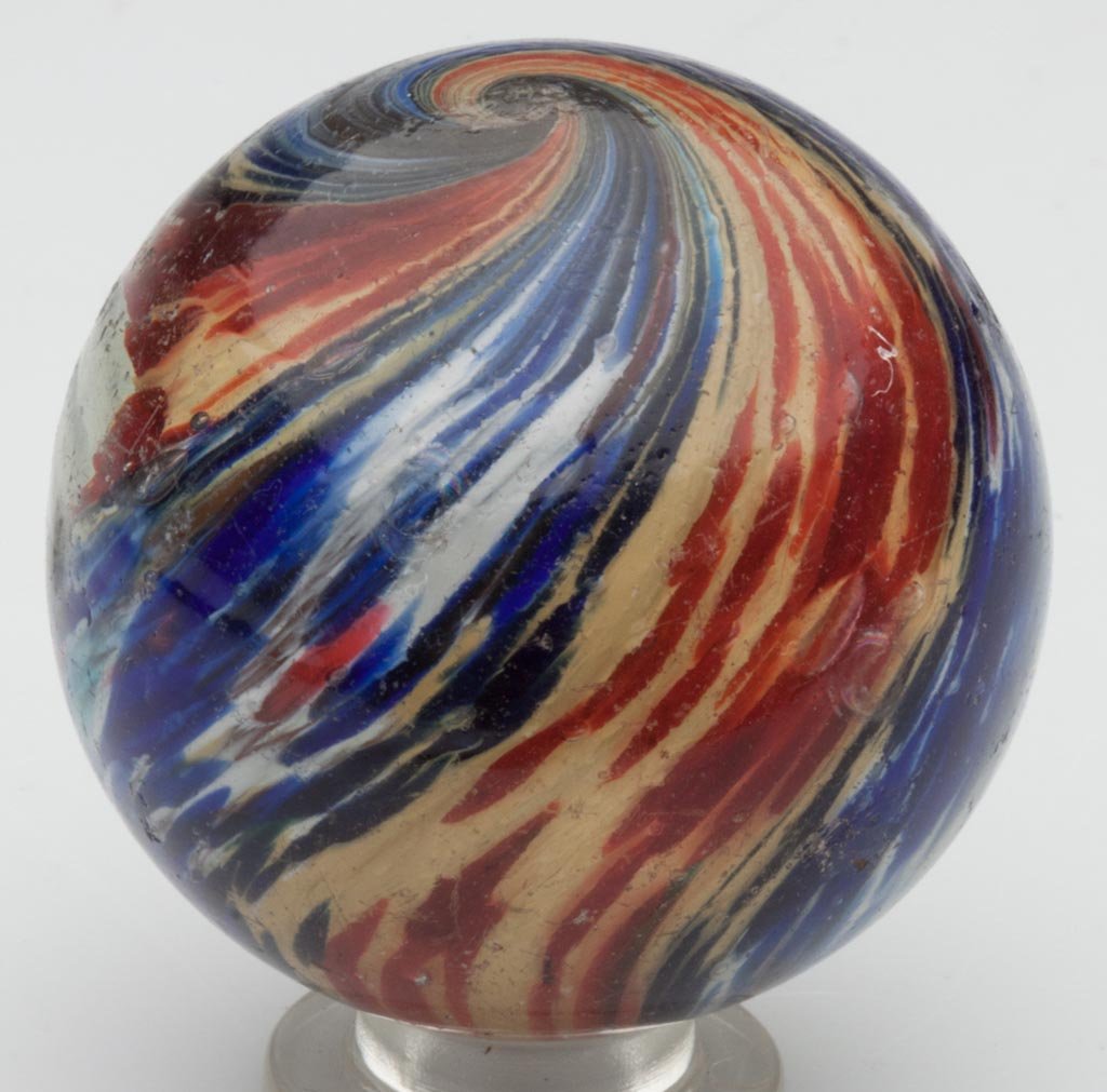 ONIONSKIN FOUR-LOBE LARGE MARBLE: ONIONSKIN FOUR-LOBE LARGE MARBLE, red, yellow, blue and white with scattered rose flakes. Late 19th/early 20th century. 2" D. Provenance: From the collection of the late Betty Jane Renn, Sunbury, PA.