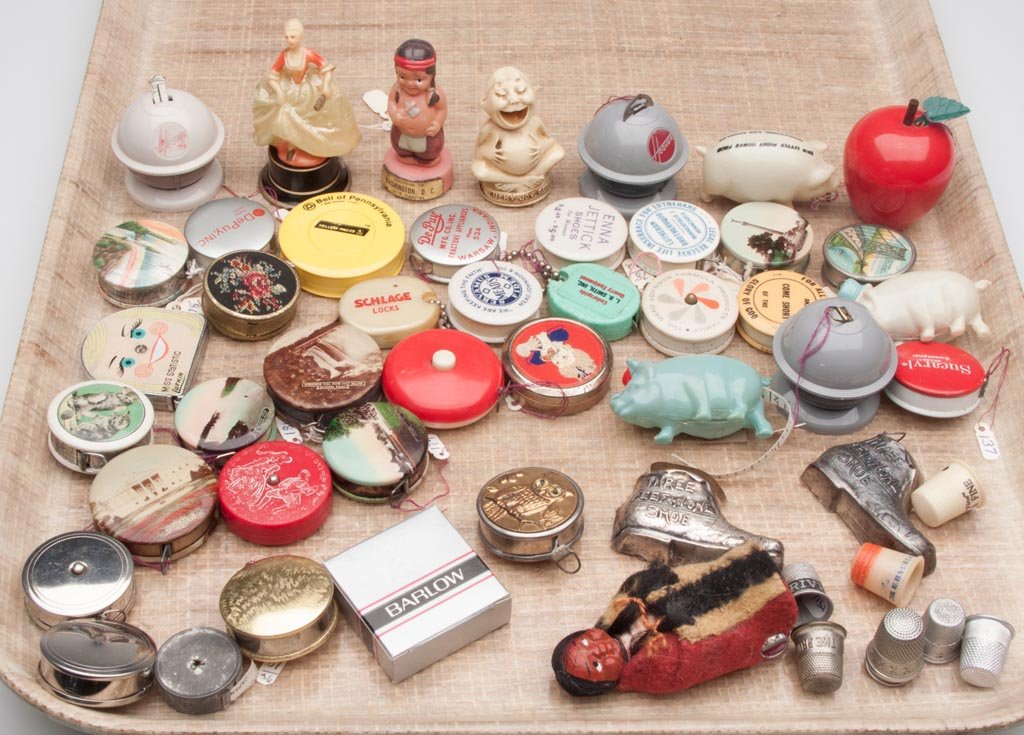 ASSORTED ADVERTISING AND NOVELTY TAPE MEASURES AND THIM: ASSORTED ADVERTISING AND NOVELTY TAPE MEASURES AND THIMBLES, LOT OF 51, comprising 43 tape measures including 13 figural, and eight advertising thimbles. 20th century. Various sizes. Provenance: From 