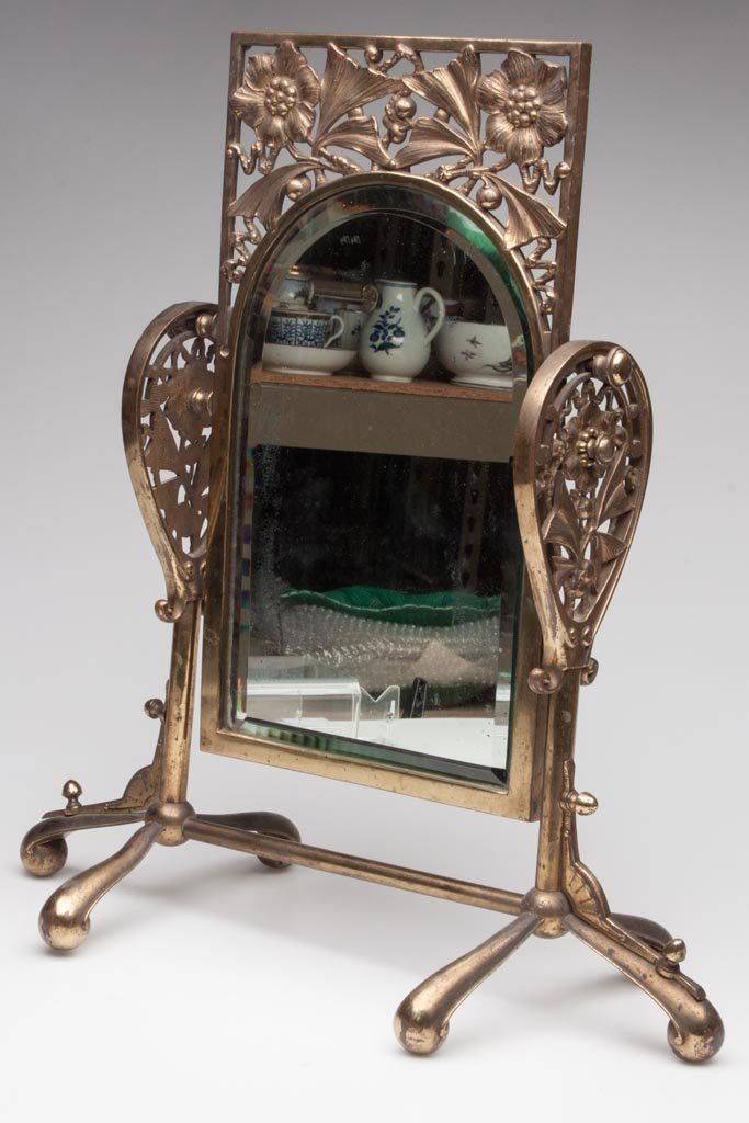AESTHETIC MOVEMENT GILT-BRASS DRESSER MIRROR: AESTHETIC MOVEMENT GILT-BRASS DRESSER MIRROR, adjustable frame with arch-top beveled mirror plate, flowering tree ornamentation. Fourth quarter 19th century. 20 1/2" HOA, 19 1/2" WOA. Provenance: Prop