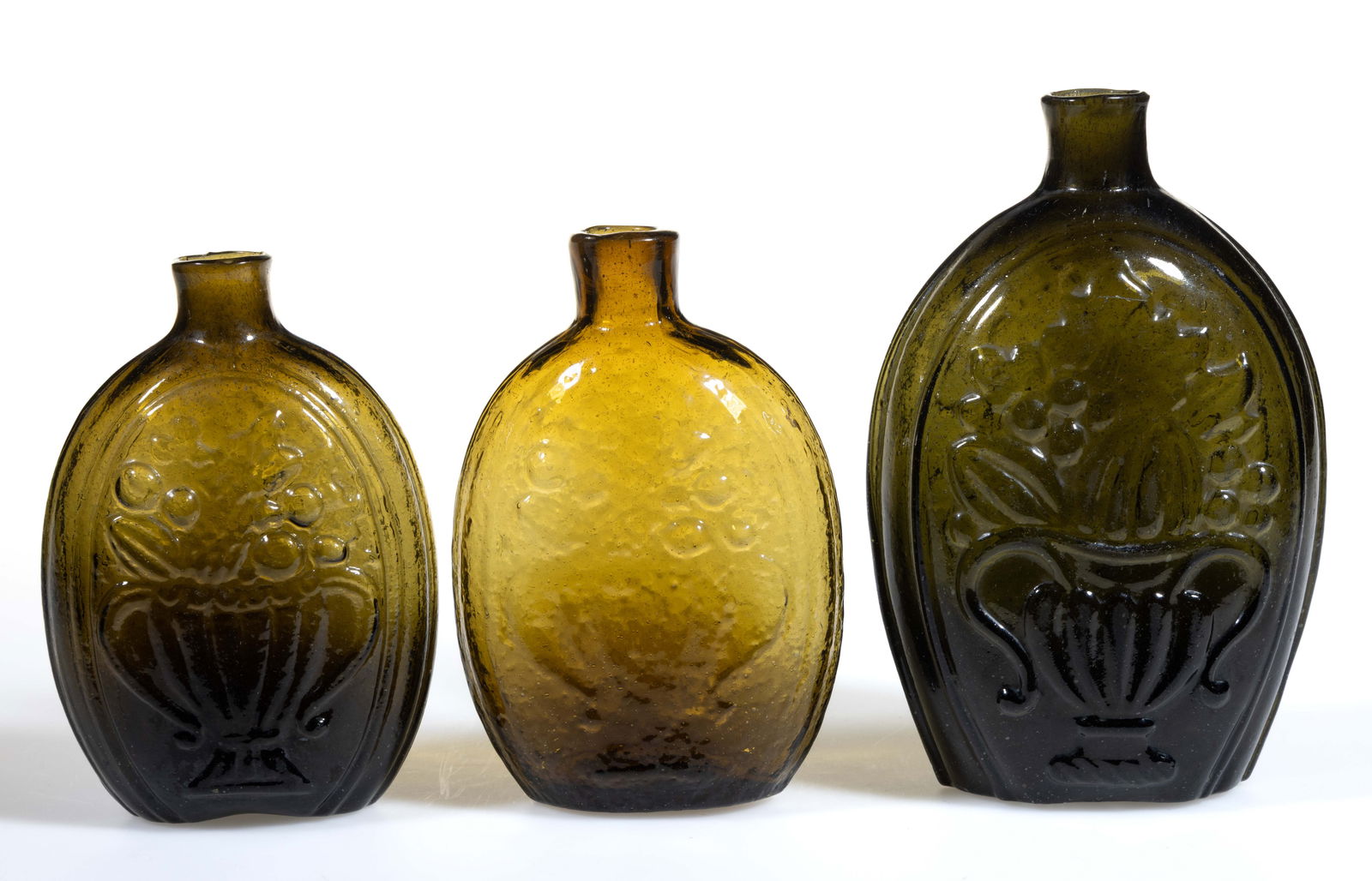 ASSORTED CORNUCOPIA - URN PICTORIAL / HISTORICAL FLASKS, LOT OF THREE: ASSORTED CORNUCOPIA - URN PICTORIAL / HISTORICAL FLASKS, LOT OF THREE, olive green and yellow olive-amber, each having one side embossed with a fruit-filled cornucopia coiled to the left&nbs