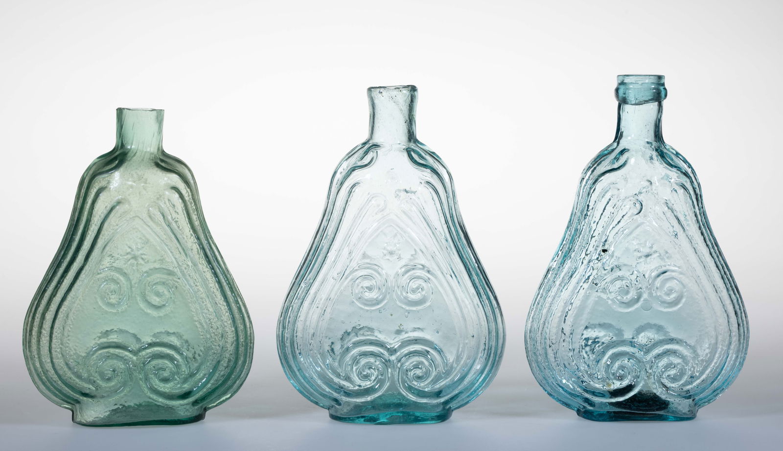 ASSORTED PINT-SIZED SCROLL FIGURED HISTORICAL FLASKS, LOT OF THREE: ASSORTED PINT-SIZED SCROLL FIGURED HISTORICAL FLASKS, LOT OF THREE, aquamarine in shades of blue and green, each with straight sheared and tooled mouths and rough pontil marks to unders