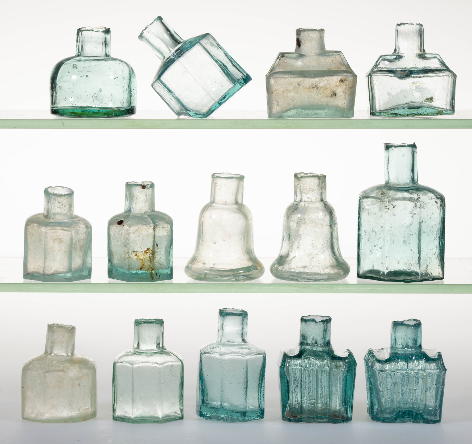 ASSORTED ENGLISH GLASS INK BOTTLES / INKWELLS, LOT OF 14: ASSORTED ENGLISH GLASS INK BOTTLES / INKWELLS, LOT OF 14, varying shades of pale blue and greenish aquamarine, including a variety of octagonal, round, square/rectangular, and two bell-form inkwe