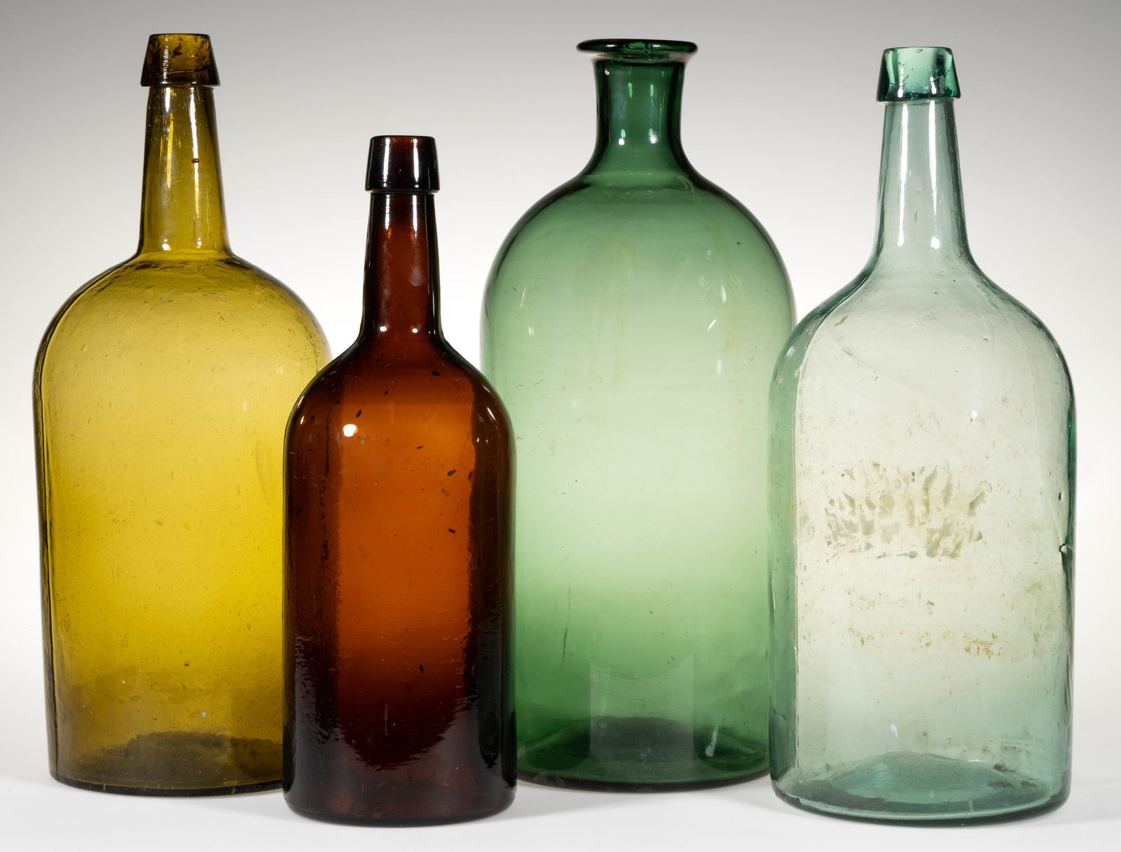 ASSORTED AMERICAN BLOWN-MOLDED DEMIJOHNS / LARGE UTILITY BOTTLES, LOT OF FOUR: ASSORTED AMERICAN BLOWN-MOLDED DEMIJOHNS / LARGE UTILITY BOTTLES, LOT OF FOUR, various colors, comprising three cylindrical long-necked examples (one amber, one golden yellow, and one greenish aquamar