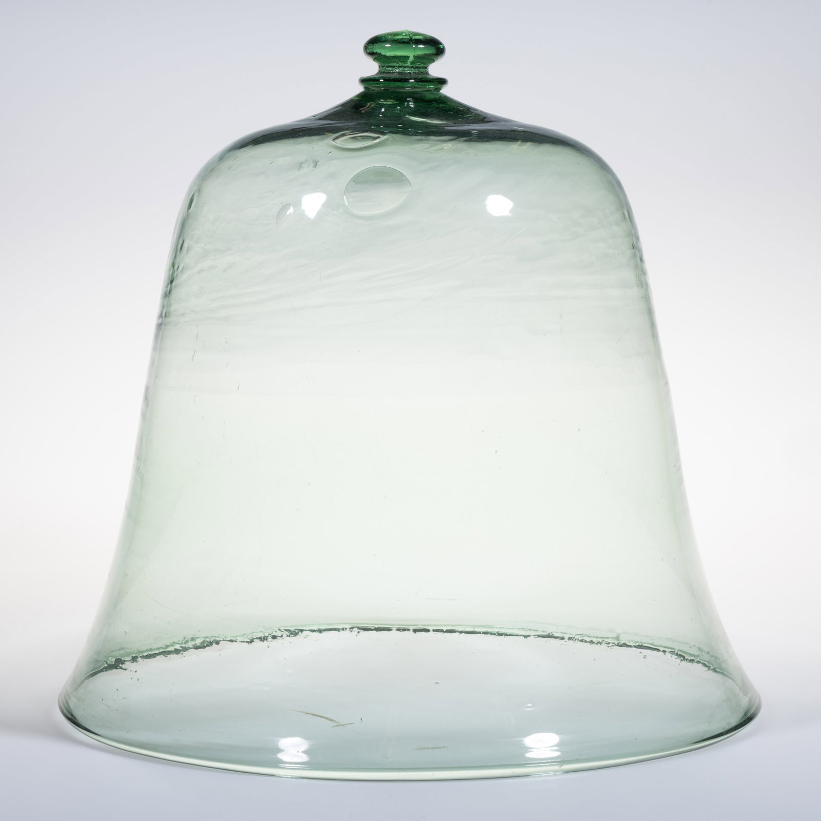 LARGE-SIZED FREE-BLOWN GLASS BELL / GARDEN CLOCHE: LARGE-SIZED FREE-BLOWN GLASS BELL / GARDEN CLOCHE, light green, bell-form dome with sharp shoulder, having a molded applied handle grip/finial to top surface. American. 19th century. 15 1/2" HOA,