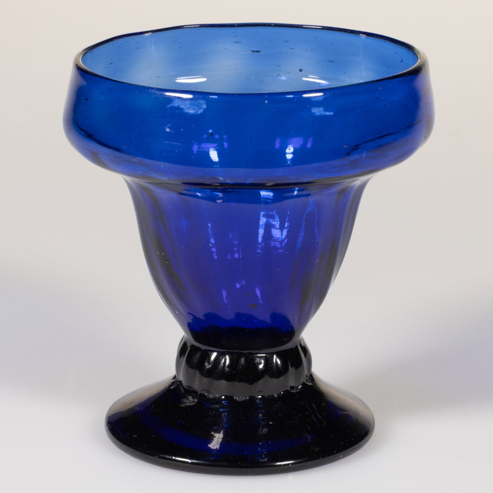 PATTERN-MOLDED RIB FOOTED GLASS OPEN SALT: PATTERN-MOLDED RIB FOOTED GLASS OPEN SALT, medium to deep blue, double-ogee bowl patterned with approximately 16 vertical ribs, raised on a short ribbed stem and an applied circular sloping 