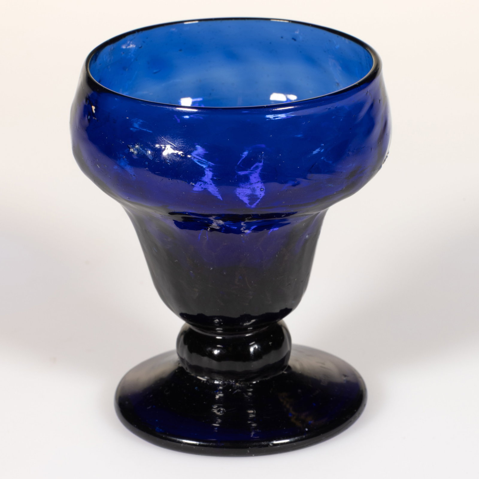 PATTERN-MOLDED DIAMOND QUILT GLASS FOOTED OPEN SALT: PATTERN-MOLDED DIAMOND QUILT GLASS FOOTED OPEN SALT, deep blue, ogee bowl with six rows of diamonds, raised on a ribbed short stem and sloping, circular foot, rough pontil mark. Midwestern, United Sta