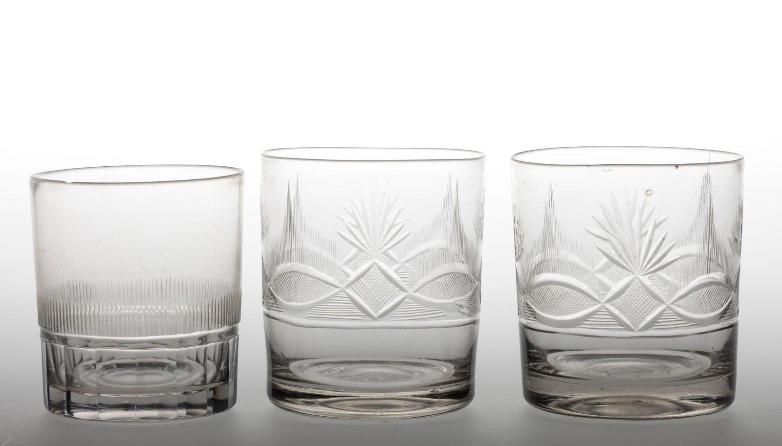 ASSORTED FREE-BLOWN AND CUT GLASS TUMBLERS, LOT OF THREE: ASSORTED FREE-BLOWN AND CUT GLASS TUMBLERS, LOT OF THREE, colorless lead glass, cylindrical forms, comprising a single example with cut-paneled base below a row of uniform blazes, and a pair patterned