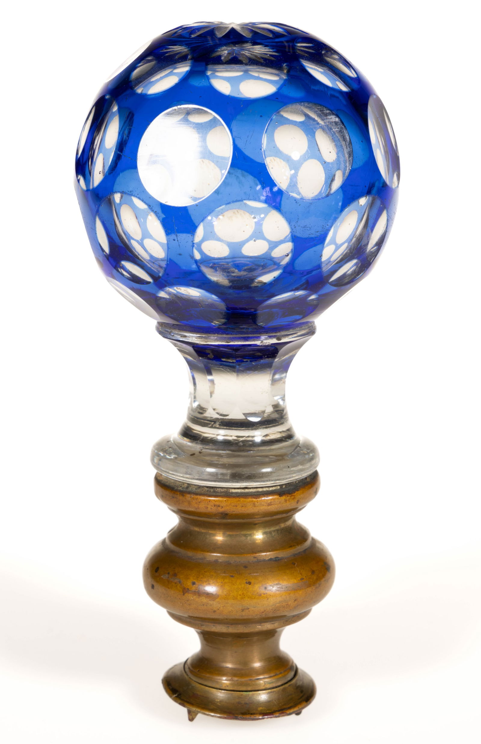CUT OVERLY PUNTY FINIAL: CUT OVERLY PUNTY FINIAL, cobalt blue to colorless, hollow spherical form with four rows of punties and a star-cut top, applied peg plastered into a brass mount. Probably for a newel post. Boston