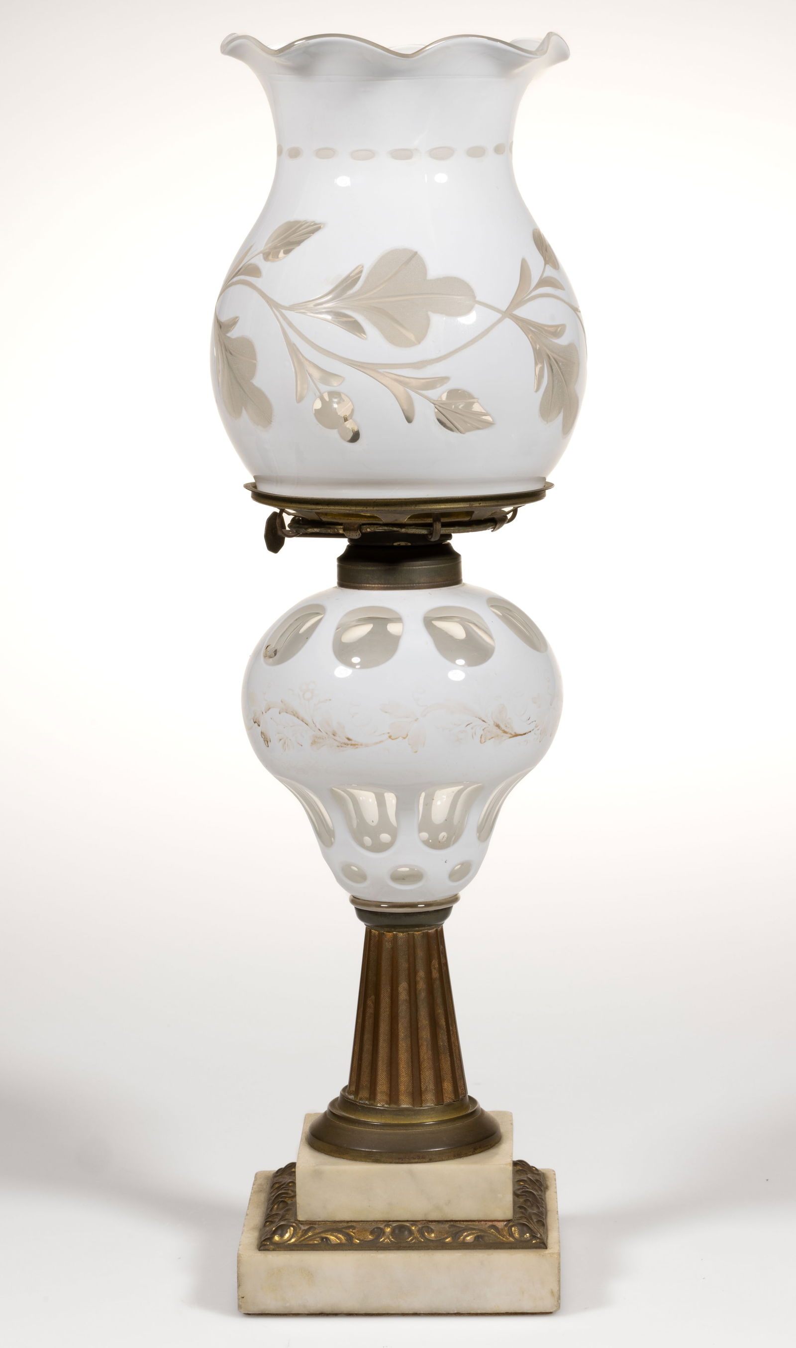 CUT OVERLAY PUNTY AND OVAL KEROSENE STAND LAMP: CUT OVERLAY PUNTY AND OVAL KEROSENE STAND LAMP, colorless cut to opaque white with traces of gilt decorated foliage band, pyriform font, brass ribbed stem, marble double-step foot with stamped br