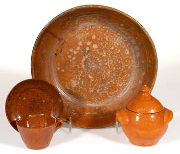JUGTOWN, NORTH CAROLINA EARTHENWARE / REDWARE ARTICLES, LOT OF THREE: JUGTOWN, NORTH CAROLINA EARTHENWARE / REDWARE ARTICLES, LOT OF THREE, lead-glazed, comprising a cup and saucer set, a covered sugar bowl with applied arched handles, and a 10" D dish. Each having