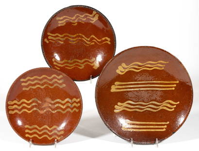 AMERICAN DECORATED EARTHENWARE / REDWARE PANS / PLATES, LOT OF THREE: AMERICAN DECORATED EARTHENWARE / REDWARE PANS / PLATES, LOT OF THREE, each single lead-glazed with yellow slip-trailed&nbsp;triple wavy line decorations&nbsp;and coggled rims, comprising one example f