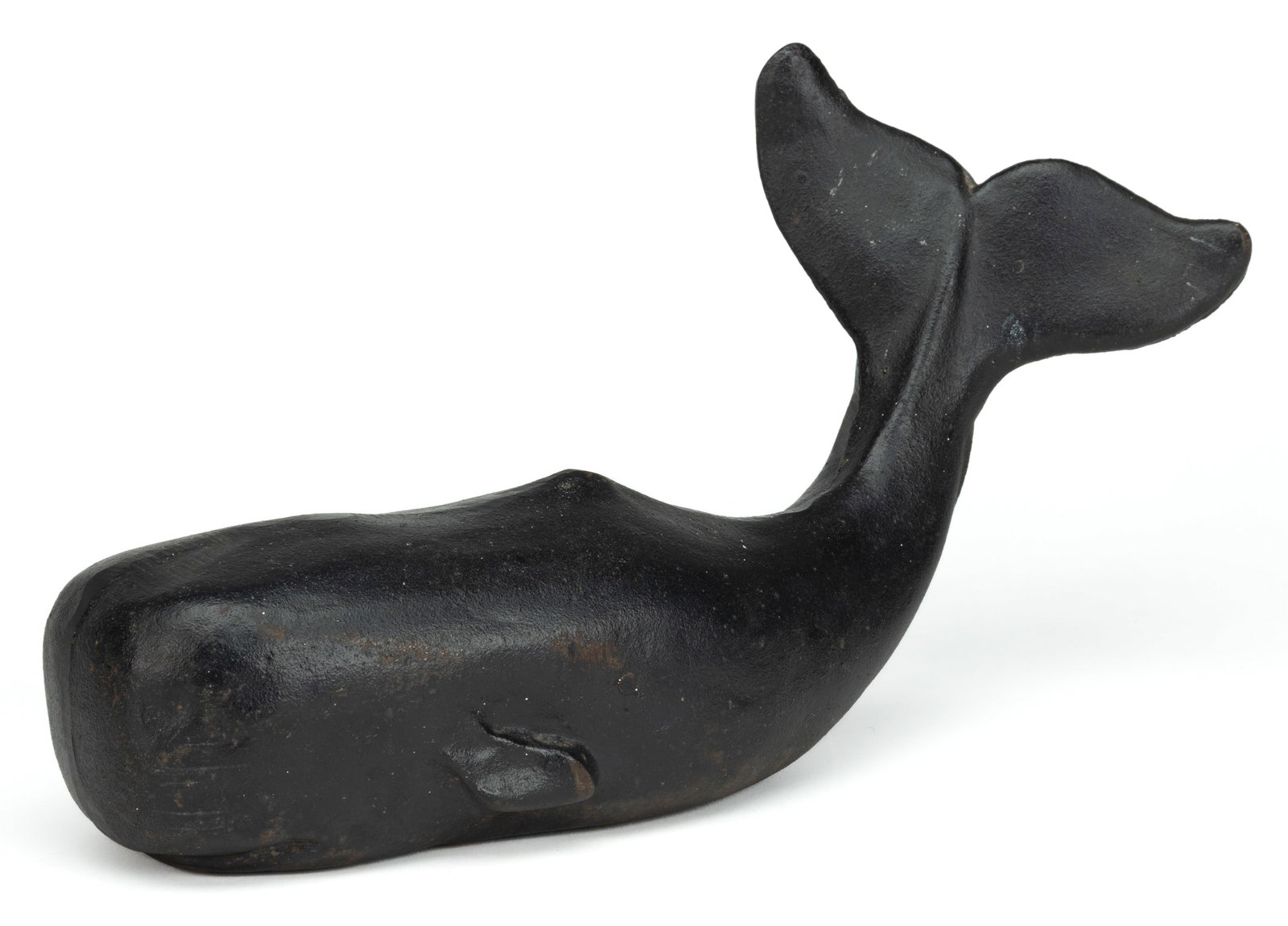 AMERICAN CAST-IRON WHALE DOORSTOP: AMERICAN CAST-IRON WHALE DOORSTOP, of hollow form, cast in two parts with a filed seam down the center, depicts a sperm whale with its tail raised. Retains an old black-painted surface. Second half 19