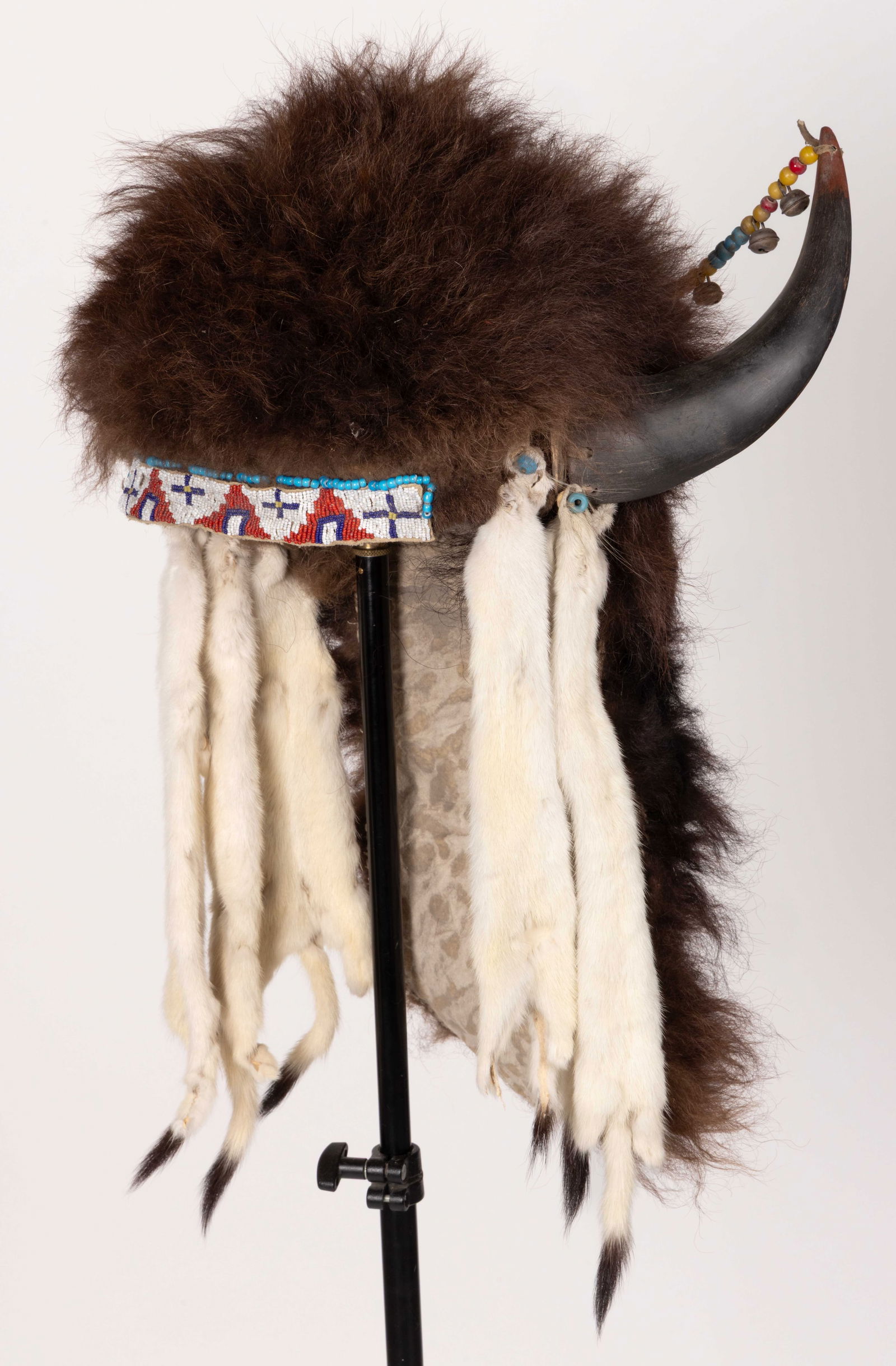 NATIVE AMERICAN PLAINS INDIAN SPLIT-HORN BUFFALO HEADDRESS WITH BEADING AND ERMINE: NATIVE AMERICAN PLAINS INDIAN SPLIT-HORN BUFFALO HEADDRESS WITH BEADING AND ERMINE, thread and other sewn, exterior of buffalo fur with fabric interior lining, having a beaded hide headband featuring