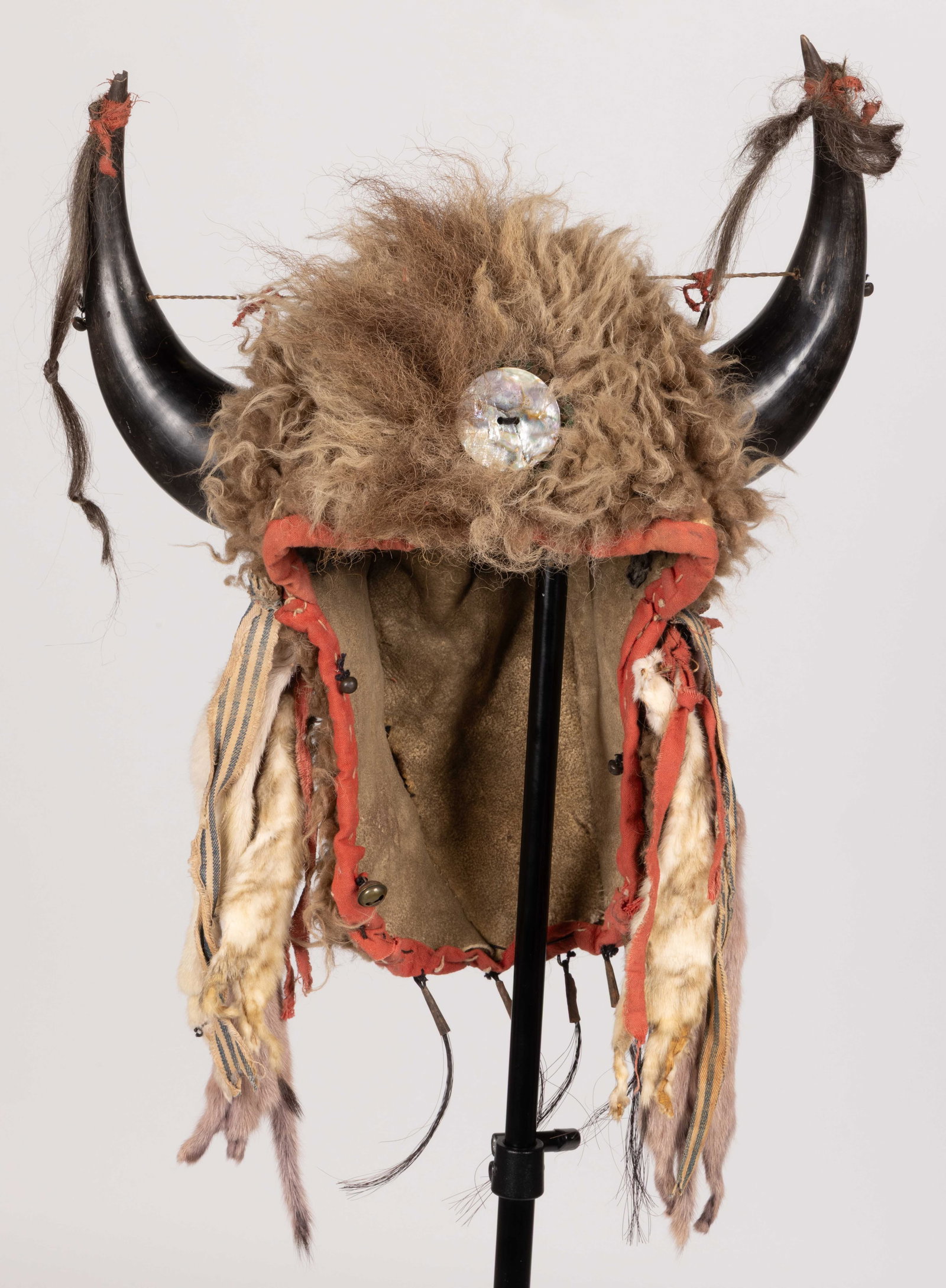 NATIVE AMERICAN PLAINS INDIAN BUFFALO HORN HIDE HEADDRESS WITH ERMINE: NATIVE AMERICAN PLAINS INDIAN BUFFALO HORN HIDE HEADDRESS WITH ERMINE, sinew and thread sewn, buffalo fur exterior topped by two full horns having tips wrapped by fabric strips and hair, sides with si