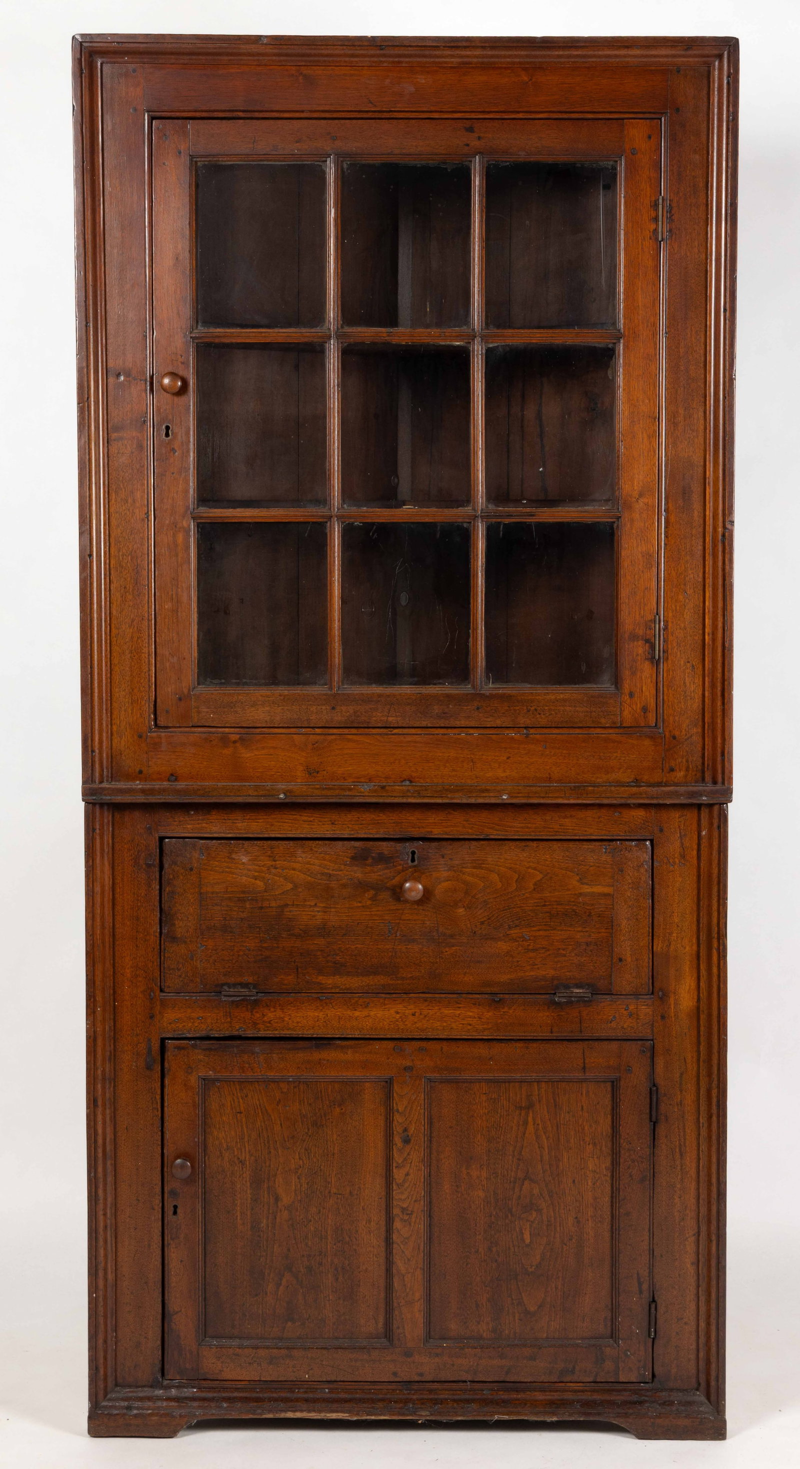 SHENANDOAH VALLEY OF VIRGINIA DIMINUTIVE WALNUT CORNER CUPBOARD: SHENANDOAH VALLEY OF VIRGINIA DIMINUTIVE WALNUT CORNER CUPBOARD, two-piece form, the upper case featuring a glazed nine-pane hinged door surrounded by a deep picture-frame molding; the lower case