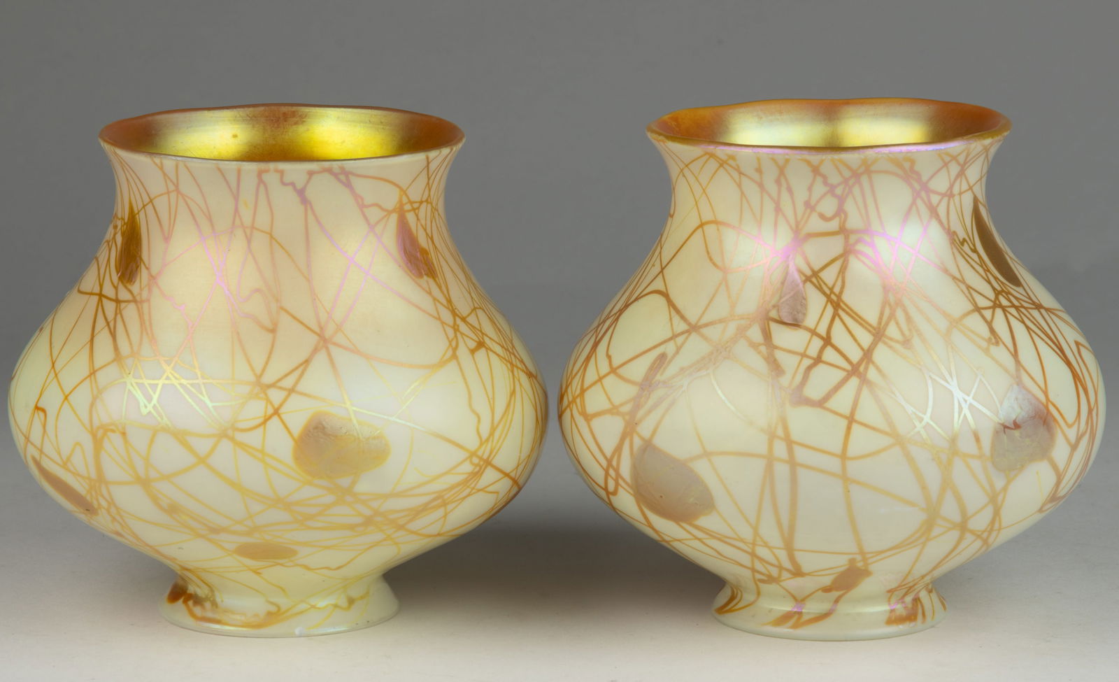 PAIR OF SIGNED STEUBEN IRIDESCENT ART GLASS HEART AND VINE LAMP SHADES: PAIR OF SIGNED STEUBEN IRIDESCENT ART GLASS HEART AND VINE LAMP SHADES, Calcite over Gold Aurene with gold exterior threading in a leaf and vine design, shape no. 2242, factory-ground fitter with etch