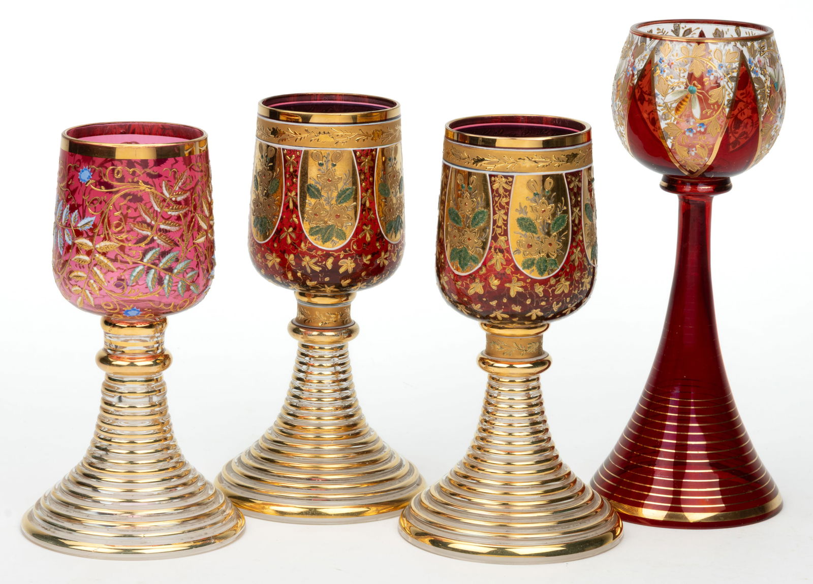 BOHEMIAN GILT AND ENAMEL-DECORATED ROEMER-TYPE WINE GLASSES, LOT OF FOUR: BOHEMIAN GILT AND ENAMEL-DECORATED ROEMER-TYPE WINE GLASSES, LOT OF FOUR, three examples of identical form having a cranberry bowl raised on a funnel-form molded colorless foot with ringed top surface