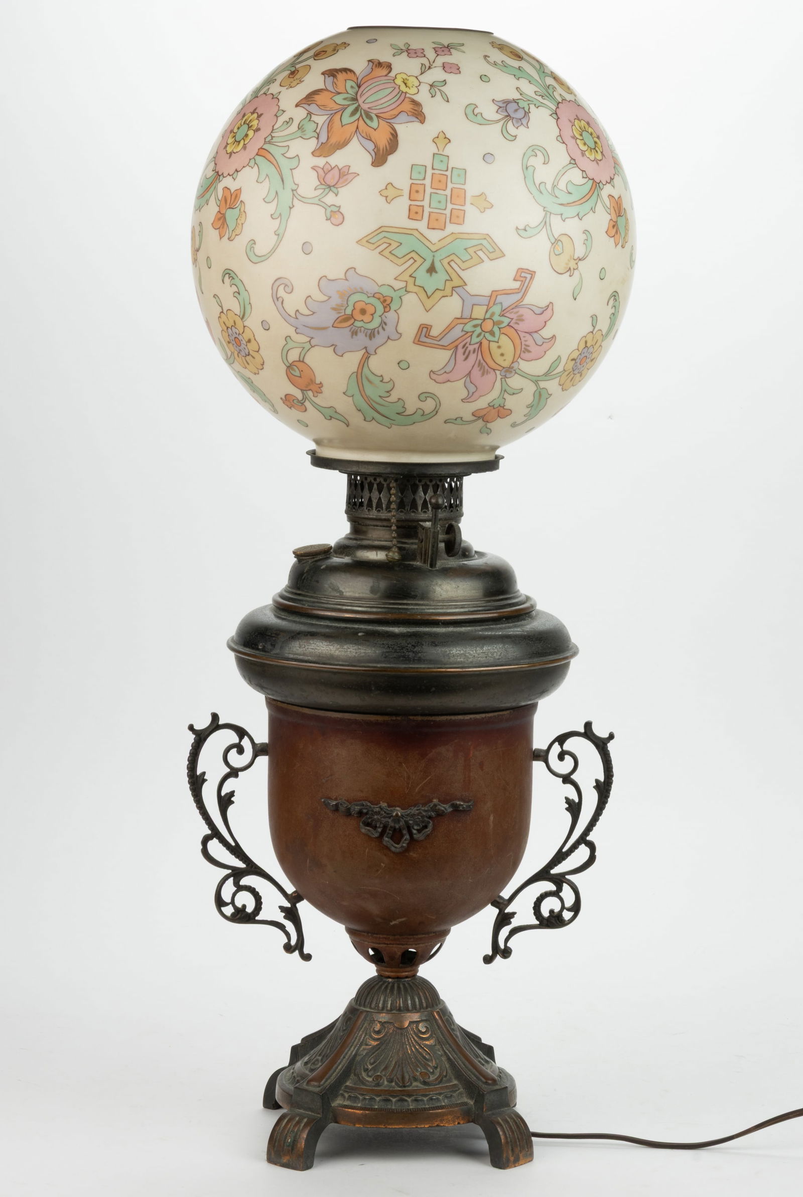 MIXED METALS KEROSENE TABLE / PARLOR LAMP: MIXED METALS KEROSENE TABLE / PARLOR LAMP, urn-form copper finished font holder raised on a conical-form base with scroll pattern and four ribbed and short feet, top of urn with a multi-stepped brass