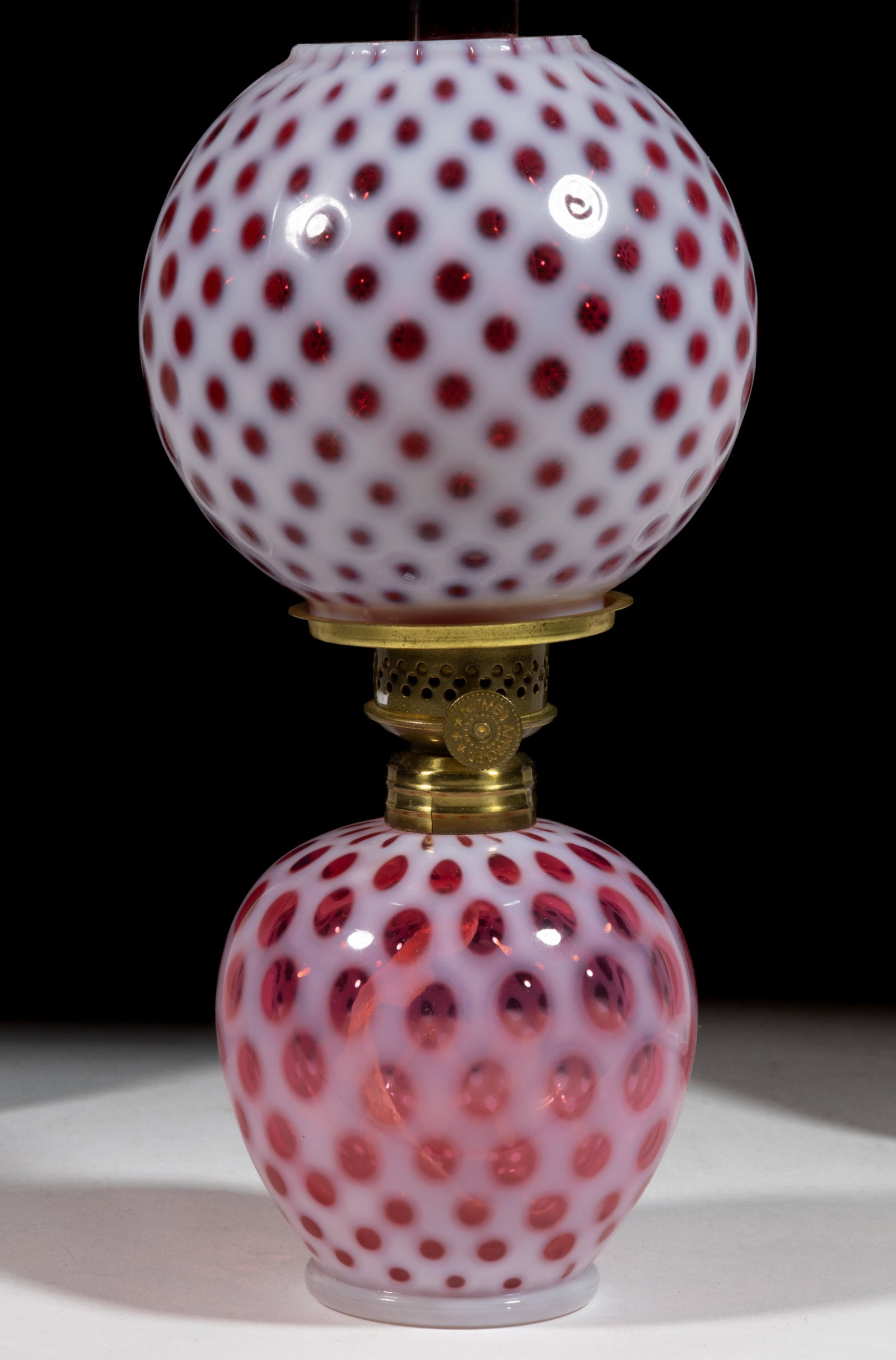 L. G. WRIGHT OPALESCENT EYE DOT MINIATURE LAMP: L. G. WRIGHT OPALESCENT EYE DOT MINIATURE LAMP, cranberry opalescent, elongated-form font, matching patterned large ball-form shade. Fitted with a Nutmeg Approved burner. L. G. Wright Glass Co. Mid 20