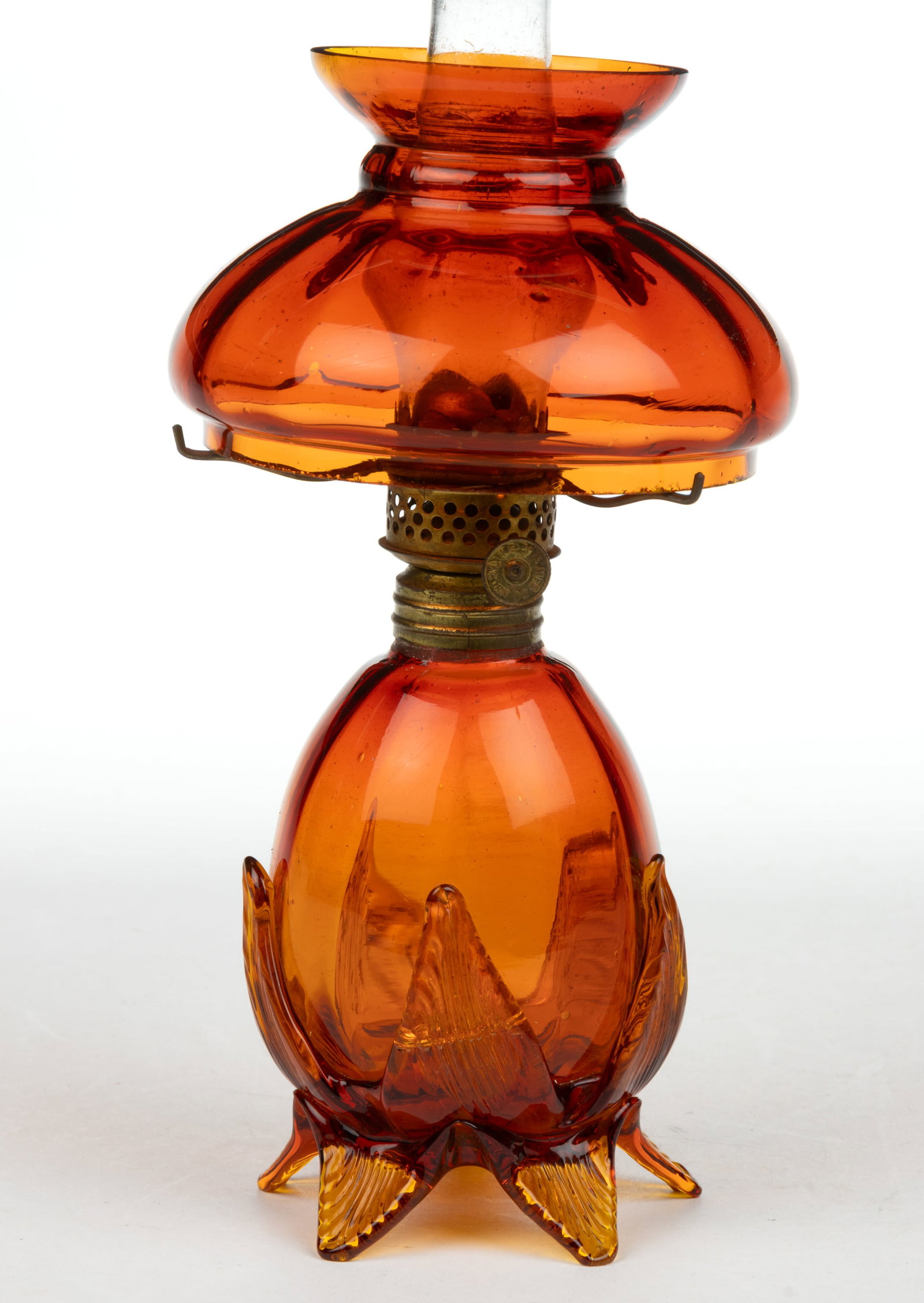 PANEL-OPTIC ART GLASS MINIATURE LAMP: PANEL-OPTIC ART GLASS MINIATURE LAMP, very deep amberina, elongated-form font, applied dark honey-amber base raised on five toes and five leaf ornaments supporting the font body, each with a pressed r