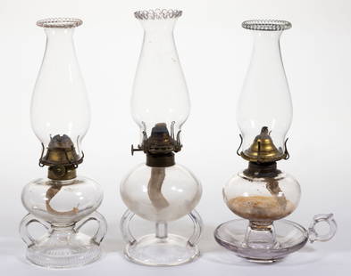 ASSORTED PATTERNED KEROSENE FOOTED FINGER LAMPS, LOT OF THREE: ASSORTED PATTERNED KEROSENE FOOTED FINGER LAMPS, LOT OF THREE, colorless, comprising two Ripley examples with double handles, undersides of foot with prism patterns, one example with a stippled square