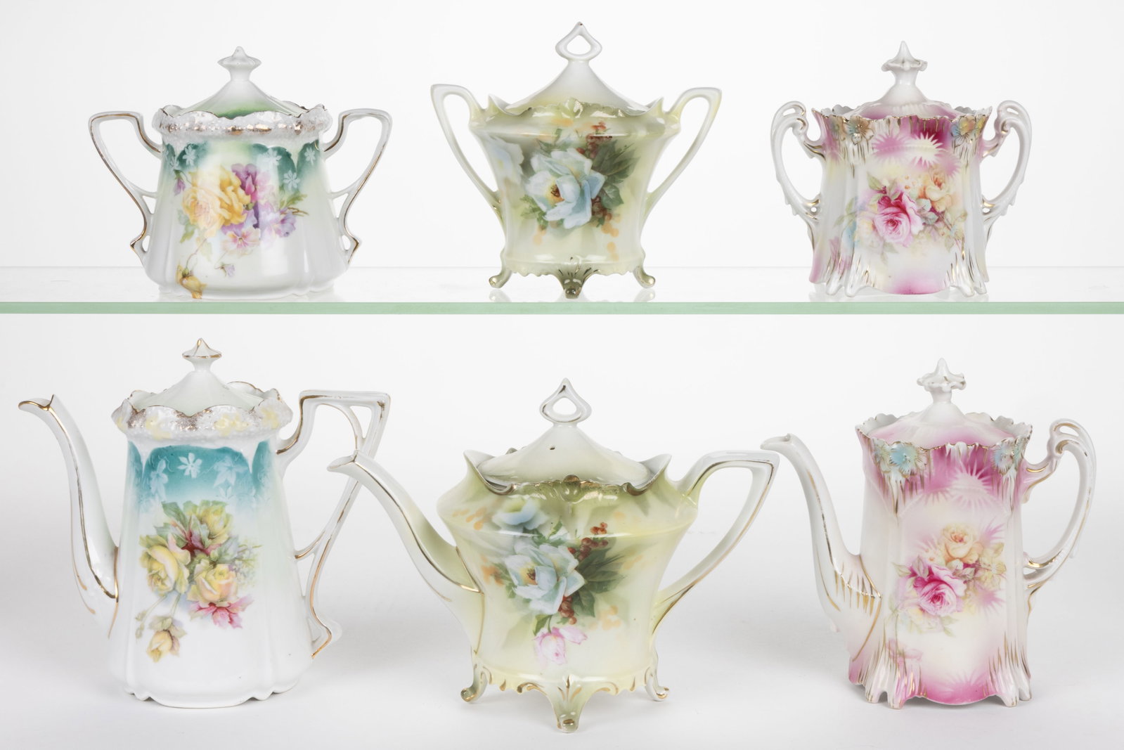 R.S. PRUSSIA PORCELAIN FLORAL MOTIF TEA ARTICLES, LOT OF SIX: R.S. PRUSSIA PORCELAIN FLORAL MOTIF TEA ARTICLES, LOT OF SIX, each having polychrome transfer images, comprising three matching sets consisting of a teapot and a covered sugar including a Mold 525 exa