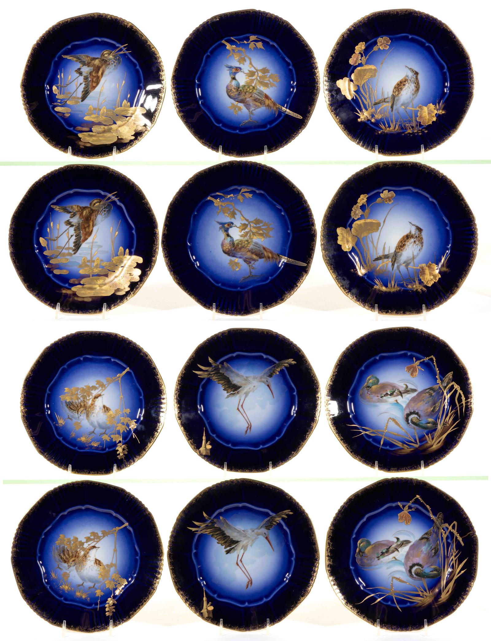 FRENCH LIMOGES PORCELAIN COBALT-DECORATED HAND-PAINTED BIRD MOTIF PLATES, SET OF 12: FRENCH LIMOGES PORCELAIN COBALT-DECORATED HAND-PAINTED BIRD MOTIF PLATES, SET OF 12, each having sponged gilt to cobalt border, comprising six different polychrome images including a white stork, a pa
