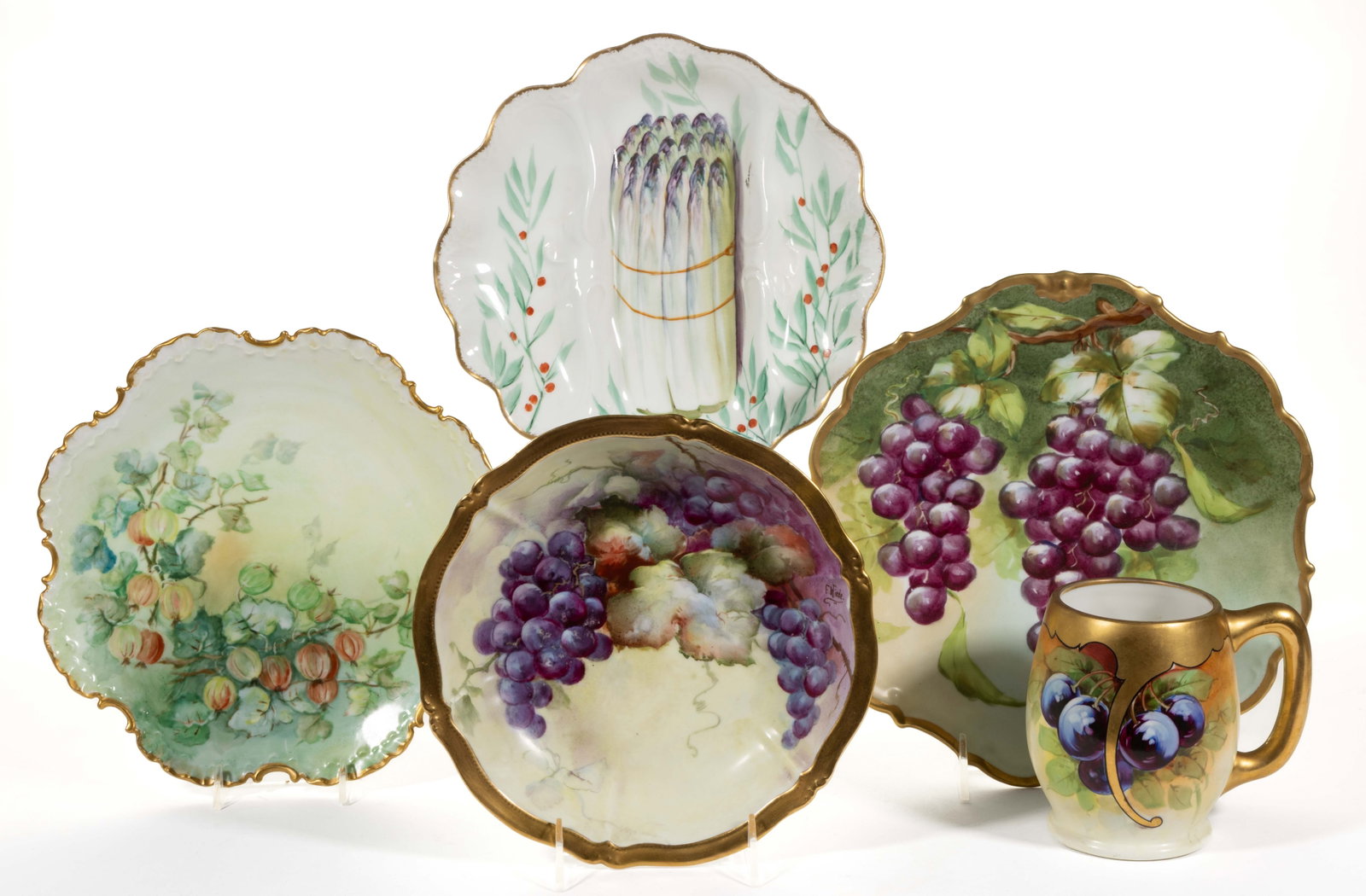 FRENCH LIMOGES / GERMAN PORCELAIN HAND-PAINTED FRUIT / VEGETABLE MOTIF ARTICLES, LOT OF FIVE: FRENCH LIMOGES / GERMAN PORCELAIN HAND-PAINTED FRUIT / VEGETABLE MOTIF ARTICLES, LOT OF FIVE, comprising an asparagus dish divided into three sections and signed "PBazudai", a barrel-form mug featurin