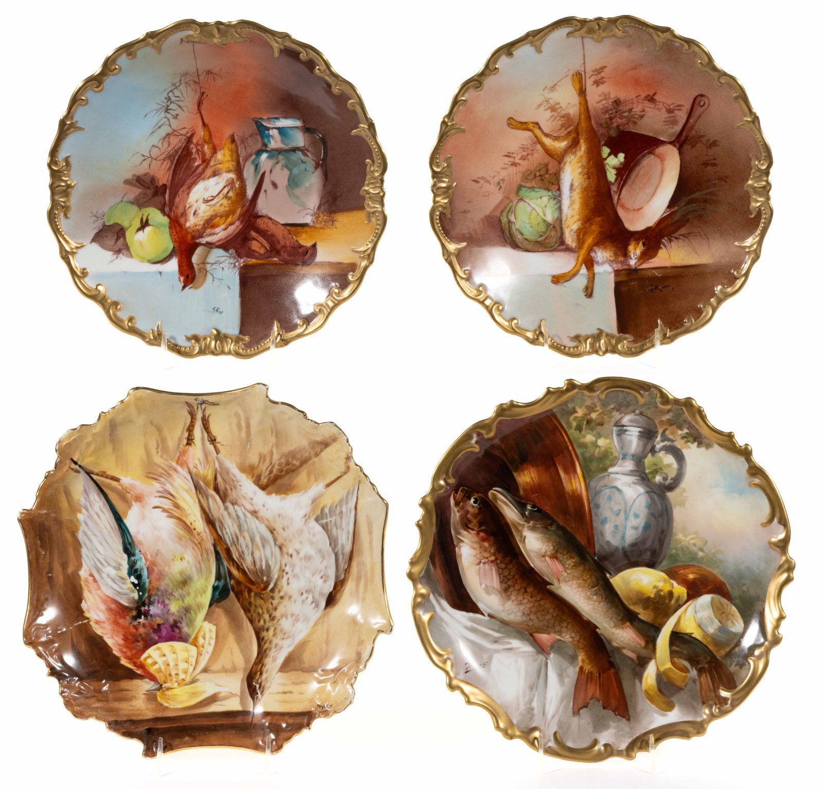 FRENCH LIMOGES PORCELAIN GAME MOTIF PLAQUES, LOT OF FOUR: FRENCH LIMOGES PORCELAIN GAME MOTIF PLAQUES, LOT OF FOUR, each having holes to foot rings for hanging, comprising one example depicting a hare hanging by one leg with pan and cabbage, one featuring fi