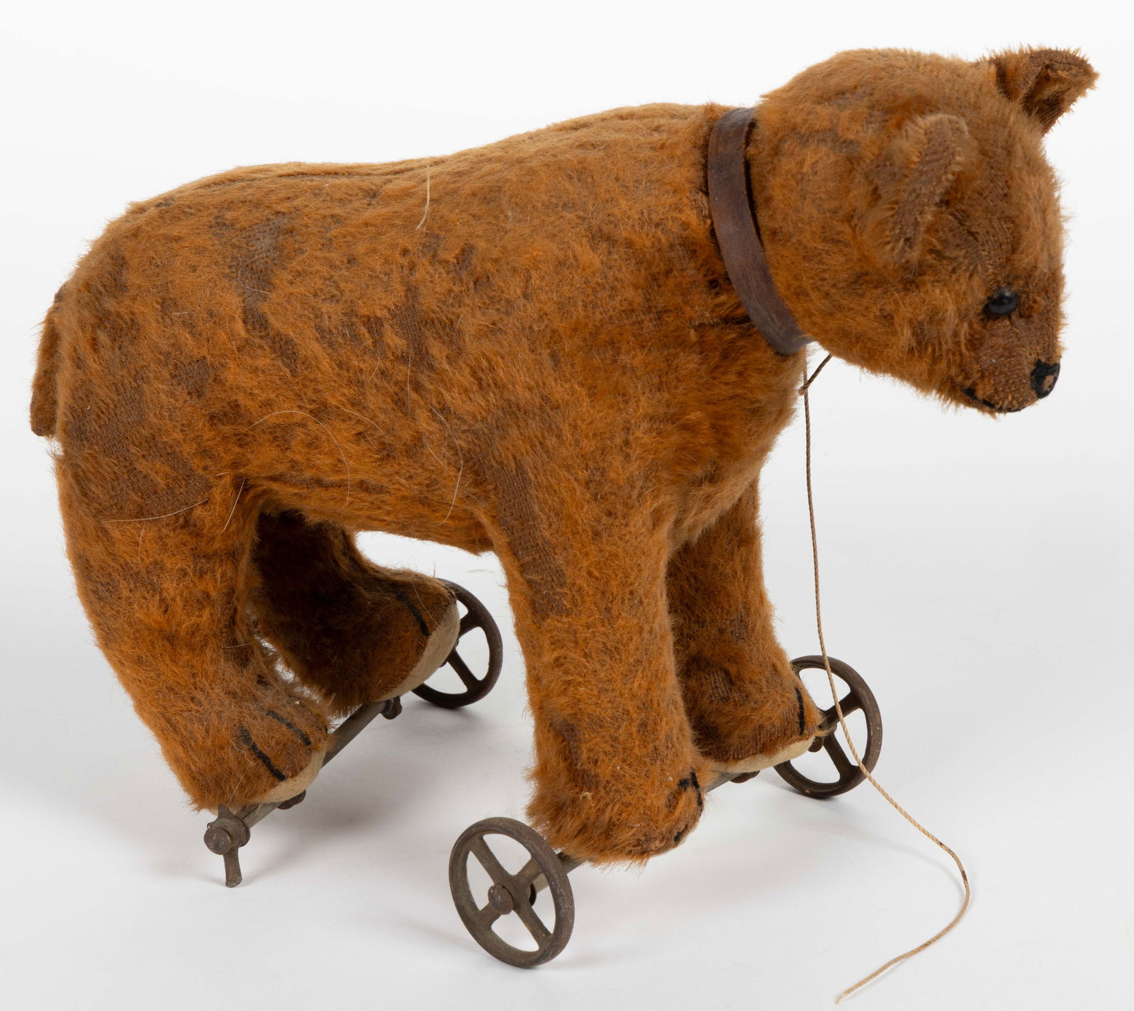 ANTIQUE FIGURAL BEAR PULL TOY: ANTIQUE FIGURAL BEAR PULL TOY, of diminutive form, light brown mohair straw-stuffed body, wooden eyes, a stitched nose and paws, the front and rear legs each have axels with wheels attached. No m