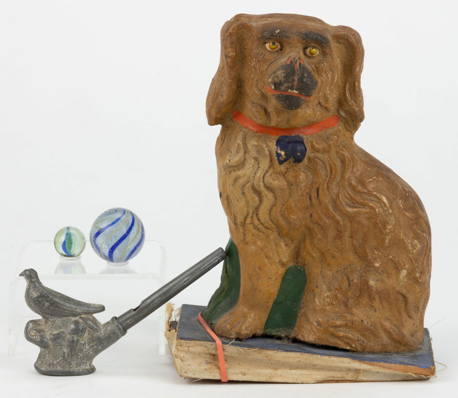 ASSORTED ANTIQUE TOYS, LOT OF FOUR: ASSORTED ANTIQUE TOYS, LOT OF FOUR, comprising a German papier-mache seated Spaniel squeaker toy, a metal bird-form whistle, and two swirl marbles. Late 19th/first quarter 20th century. 6 1/2" HO