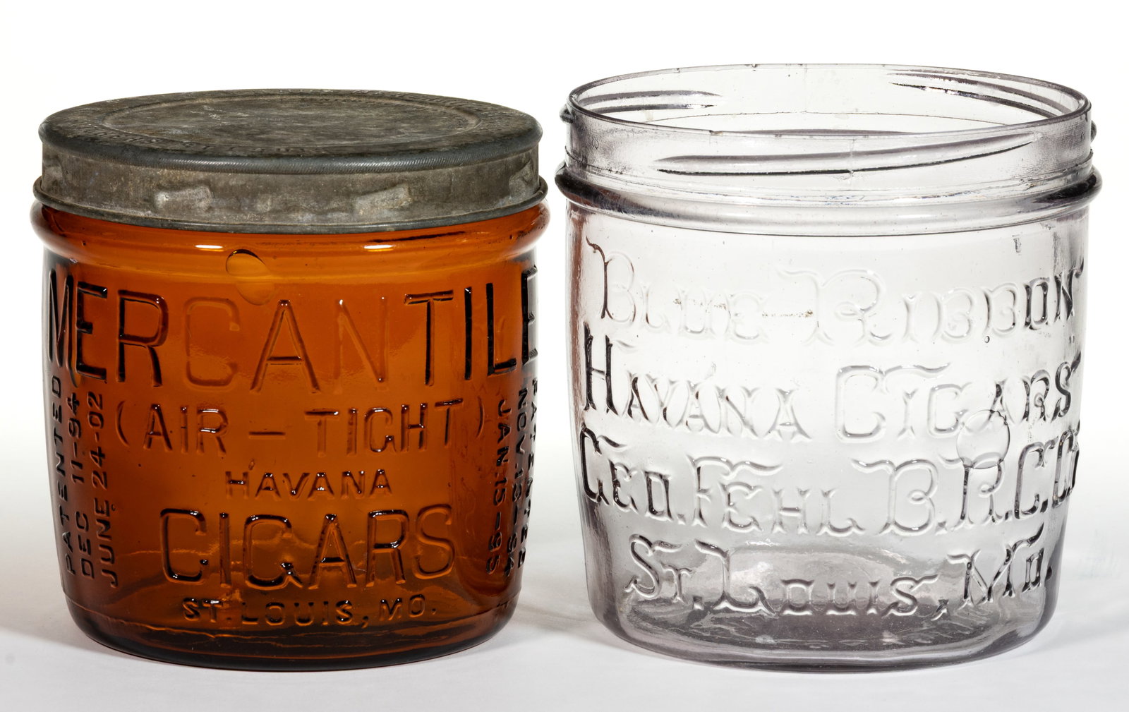 EMBOSSED GLASS TOBACCO / CIGAR ADVERTISING JARS, LOT OF TWO: EMBOSSED GLASS TOBACCO / CIGAR ADVERTISING JARS, LOT OF TWO, squat cylindrical form jars with threaded mouths, comprising one lightly sun-colored amethyst example embossed for "BLUE RIBBON / HAVA