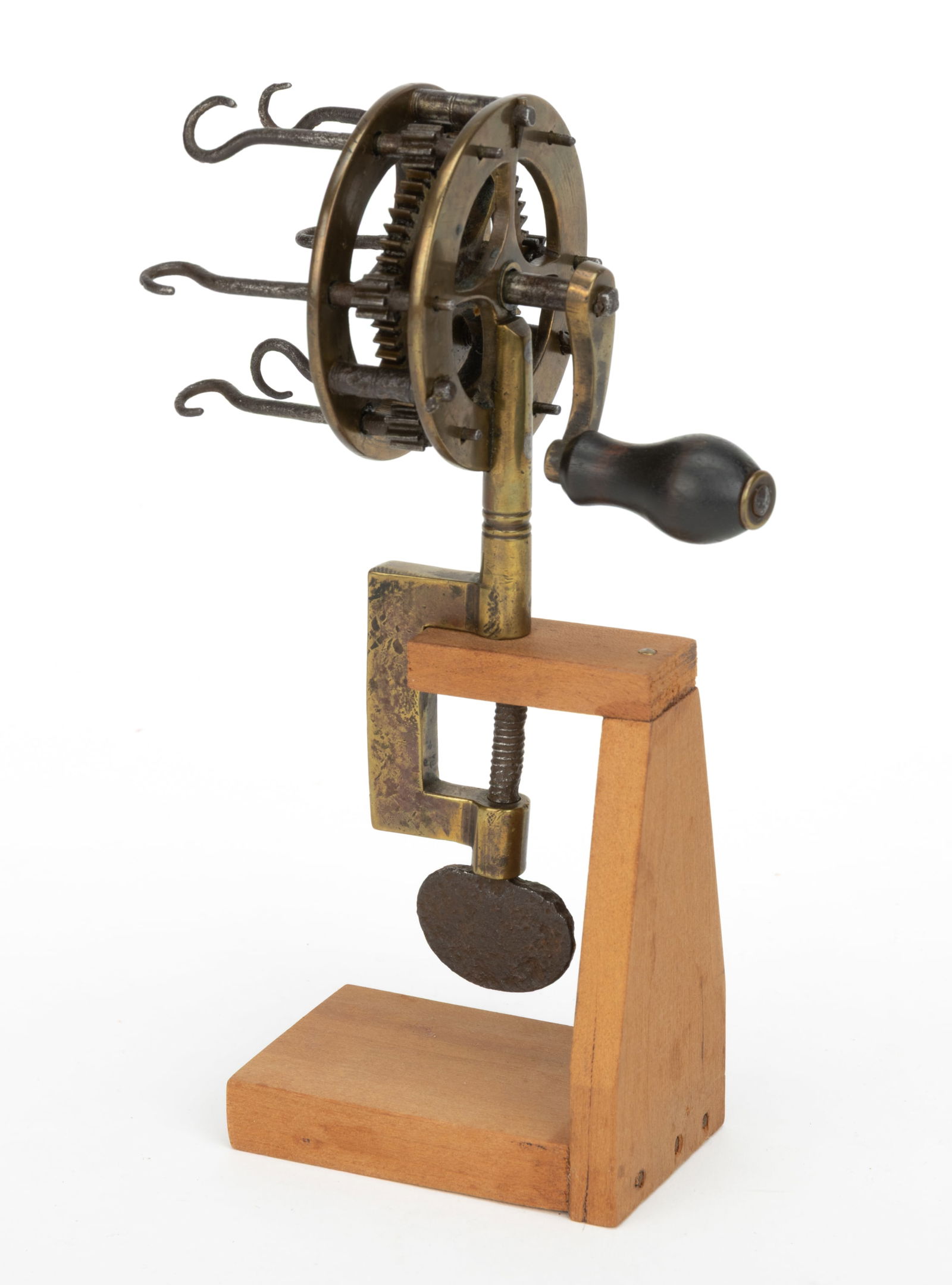 BRASS AND IRON TABLE-TOP FURLING ENGINE / TWISTING MACHINE / GUT TWISTER: BRASS AND IRON TABLE-TOP FURLING ENGINE / TWISTING MACHINE / GUT TWISTER, circular reel-form fitted with six iron hooks, iron gears and crank handle with ebony wooden handle, brass C-clamp with i