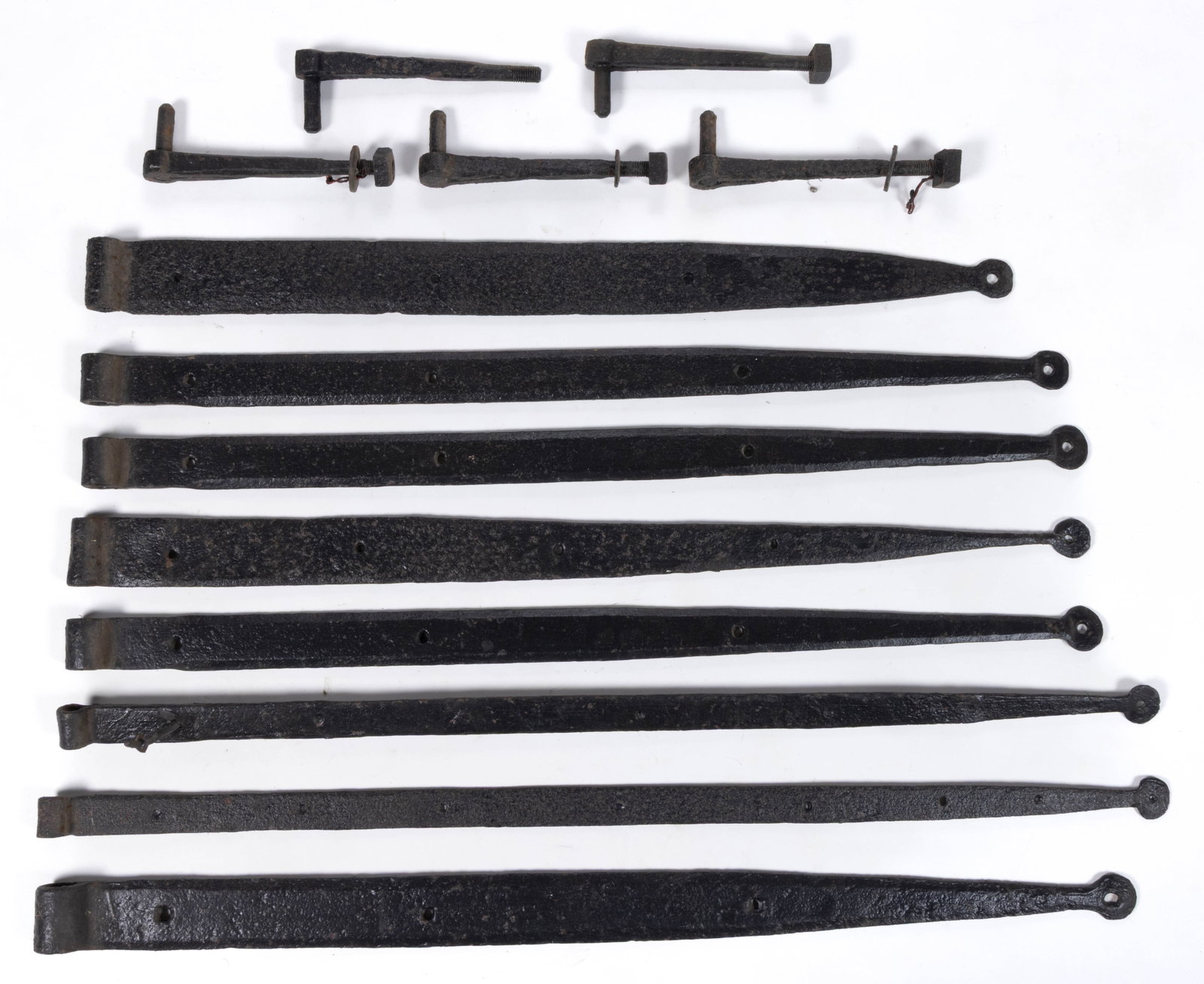 ASSORTED WROUGHT-IRON STRAP HINGES AND PINTLES, LOT OF 13: ASSORTED WROUGHT-IRON STRAP HINGES AND PINTLES, LOT OF 13, comprising eight large hinges with tips terminating in a circular form, and five pintles with threaded bolt construction. 19th century. 9 1/8