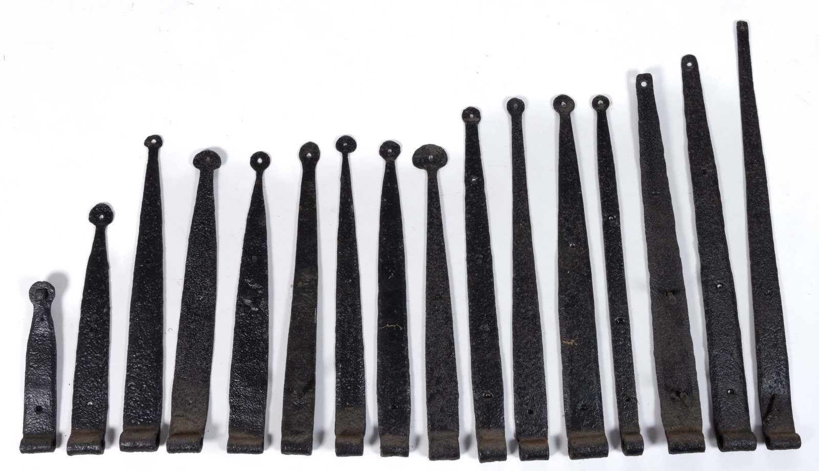 ASSORTED WROUGHT-IRON STRAP HINGES LOT OF 16: ASSORTED WROUGHT-IRON STRAP HINGES, LOT OF 16, including 12 examples with tips terminating in a circular form. 19th century. 8 3/4" to 23 3/4" LOA. Provenance: From the Lee W