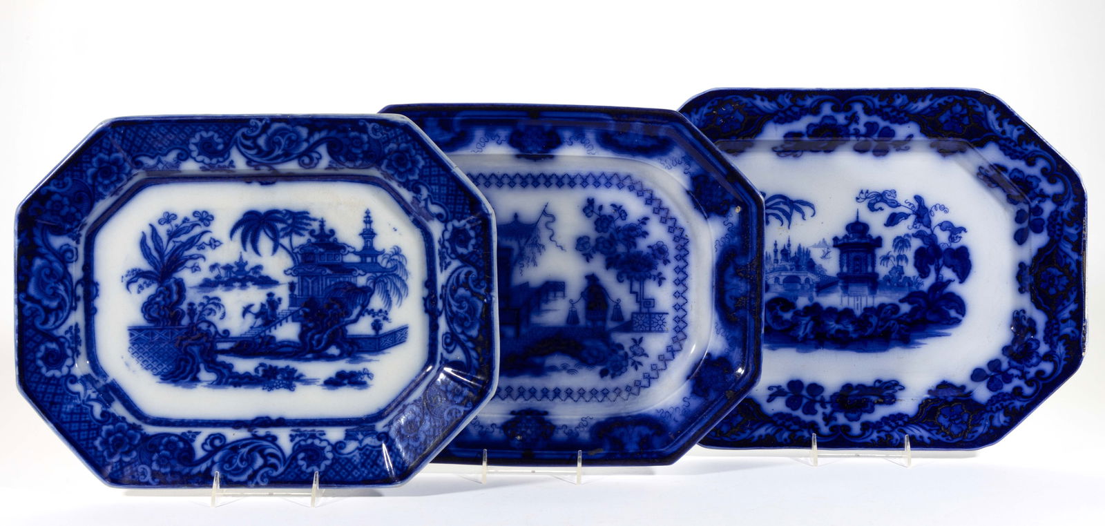 STAFFORDSHIRE FLOW BLUE IRONSTONE CHINOISERIE MOTIF PLATTERS, LOT OF THREE: STAFFORDSHIRE FLOW BLUE IRONSTONE CHINOISERIE MOTIF PLATTERS, LOT OF THREE, comprising one example with Mayer's Oregon pattern depicting a figure carrying buckets across a bridge, one example feat