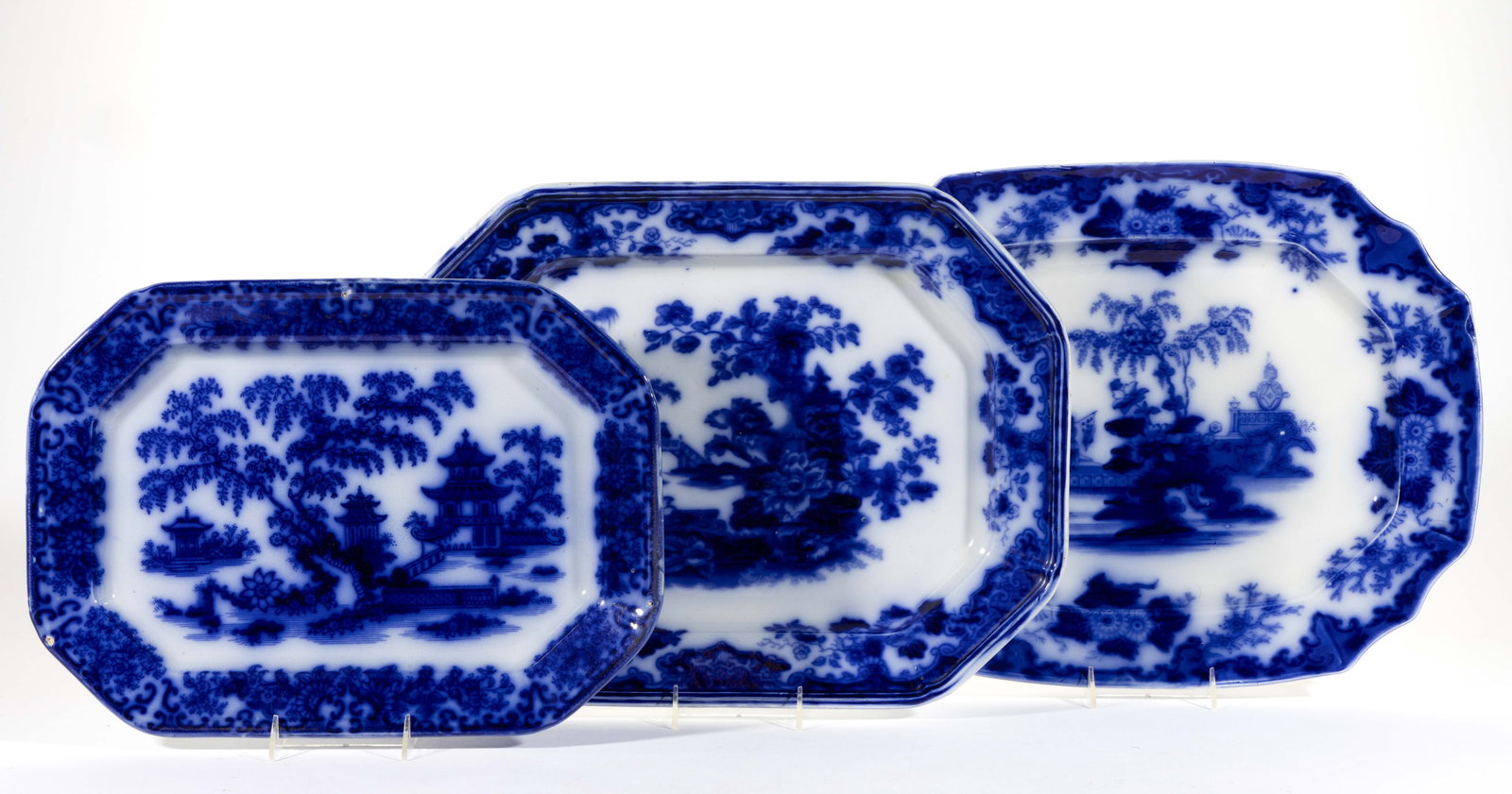 STAFFORDSHIRE FLOW BLUE IRONSTONE CHINOISERIE MOTIF PLATTERS, LOT OF THREE: STAFFORDSHIRE FLOW BLUE IRONSTONE CHINOISERIE MOTIF PLATTERS, LOT OF THREE, each of rectangular form with canted corners and having dark blue transfer scenes with printed titles to underside, comprisi