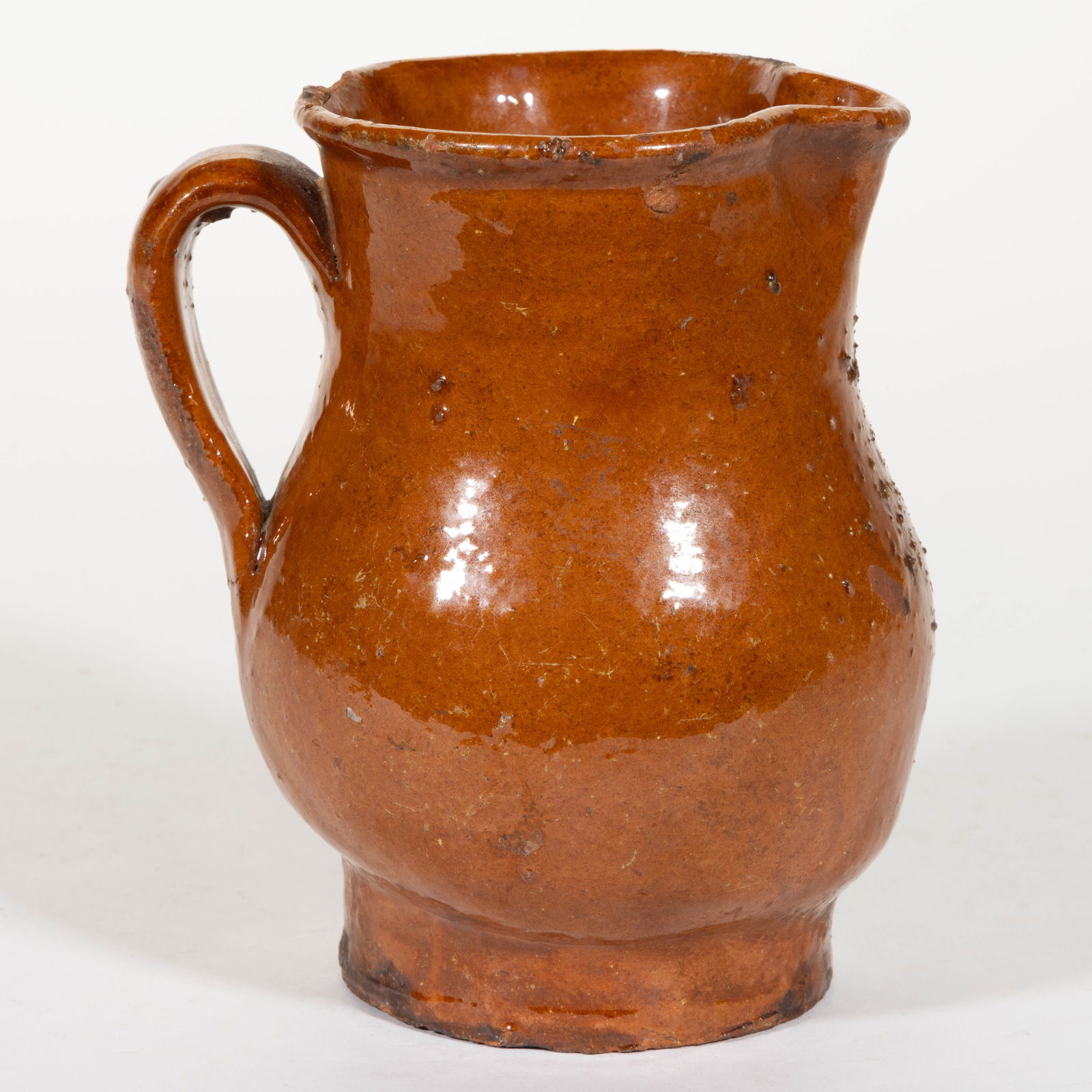 AMERICAN EARTHENWARE / REDWARE DIMINUTIVE PITCHER: AMERICAN EARTHENWARE / REDWARE DIMINUTIVE PITCHER, lead-glazed, baluster form with rounded rim, pinched spout, and applied strap handle. First half 19th century. 4 3/4" HOA. Provenance: Pro