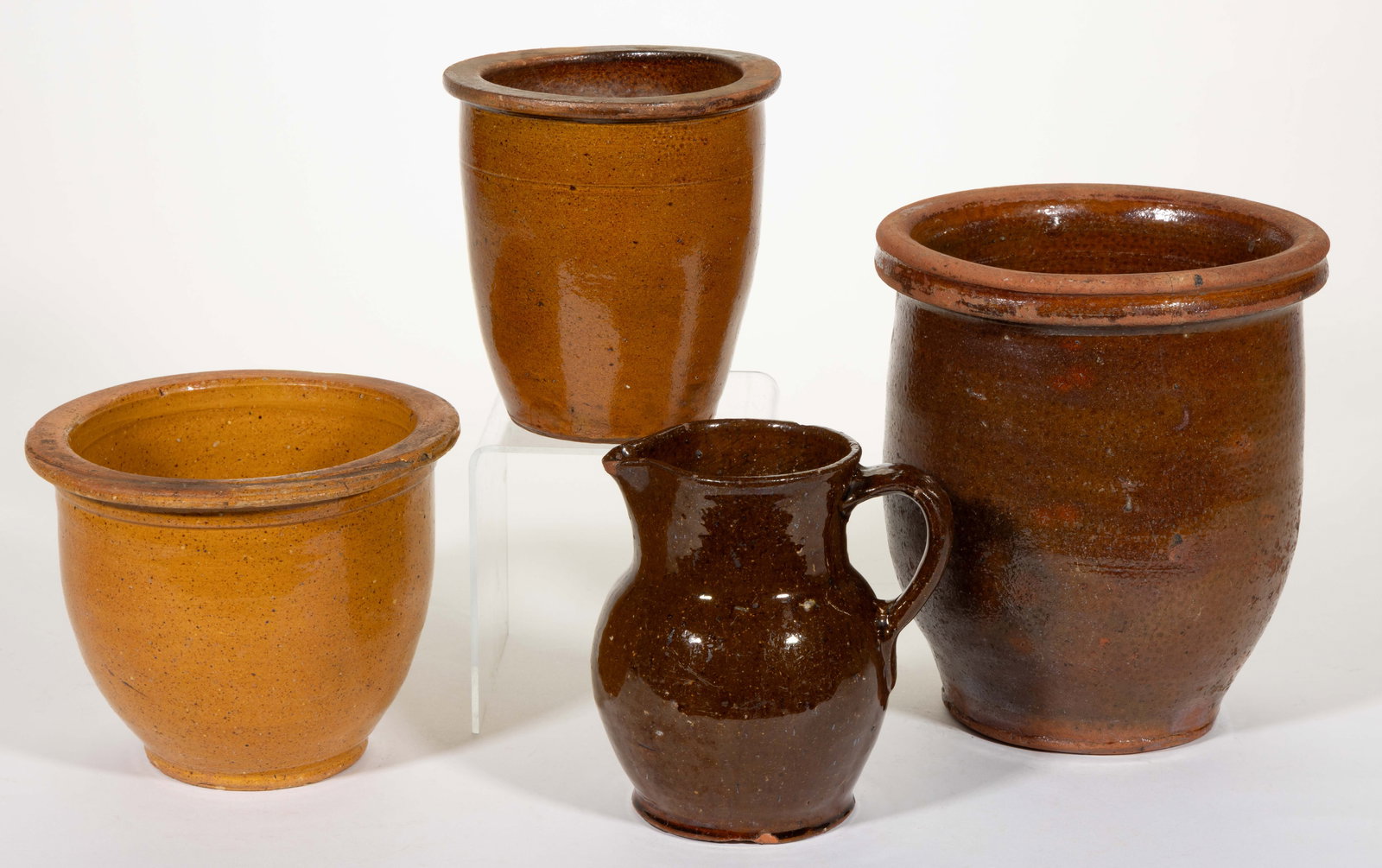 AMERICAN EARTHENWARE / REDWARE ARTICLES, LOT OF FOUR: AMERICAN EARTHENWARE / REDWARE ARTICLES, LOT OF FOUR, lead-glazed, comprising one bulbous-form pitcher with applied strap handle and three wide-mouth form crocks including two with flat-top rims and o