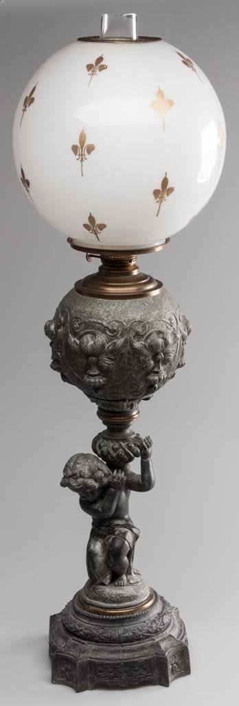 DIETZ NO. 1023 FIGURAL STEM STAND LAMP: DIETZ NO. 1023 FIGURAL STEM STAND LAMP cast-spelter embossed font with cartouche pattern and a figural cherub stem, brass connectors. Fitted with a period set-up comprising a Holmes, Booth & Haydens/J