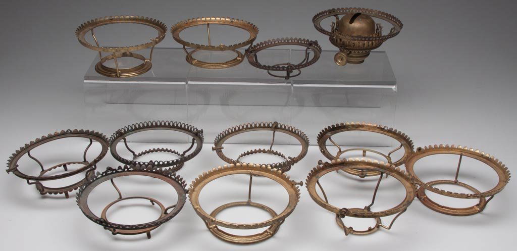 STAMPED BRASS TRIPOD TYPE SHADE HOLDERS, LOT OF 12: STAMPED BRASS TRIPOD TYPE SHADE HOLDERS, LOT OF 12, one example fitted with a No. 2 slip burner and one with patent information. Second half 19th century. 1 1/4" to 2 1/2" H, 4 1/8" and 5" D fitter. P